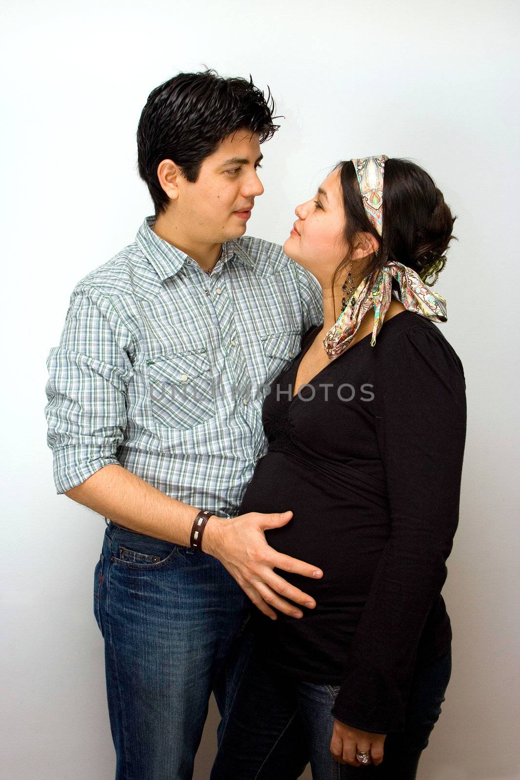 Parents expecting a baby. Father holds the belly of the mother, while parents face each other.