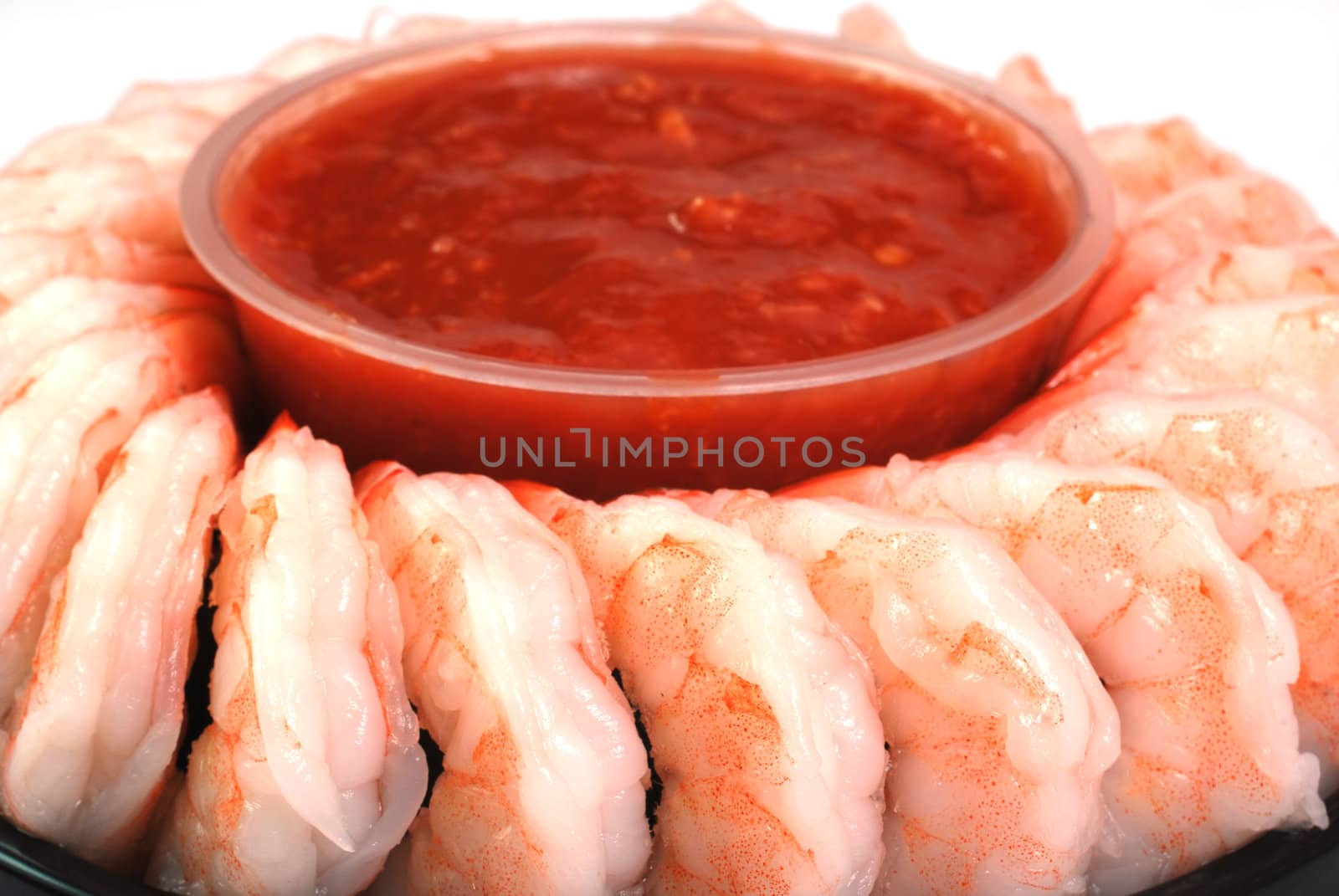 Shrimp cocktail arranged around a cup of seafood sauce.  