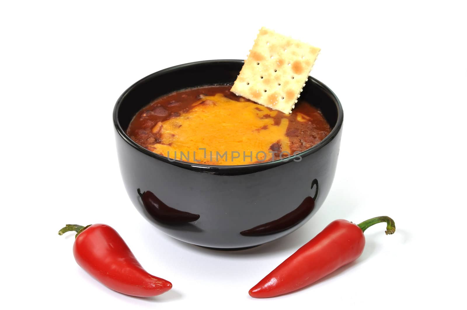 Bowl of chili with melted cheese, cracker,  and red cayenne peppers.  Isolated on white background.