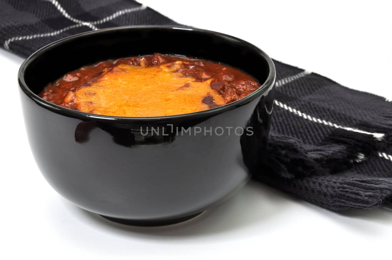 Bowl of chili with melted cheese and scarf isolated on white background.