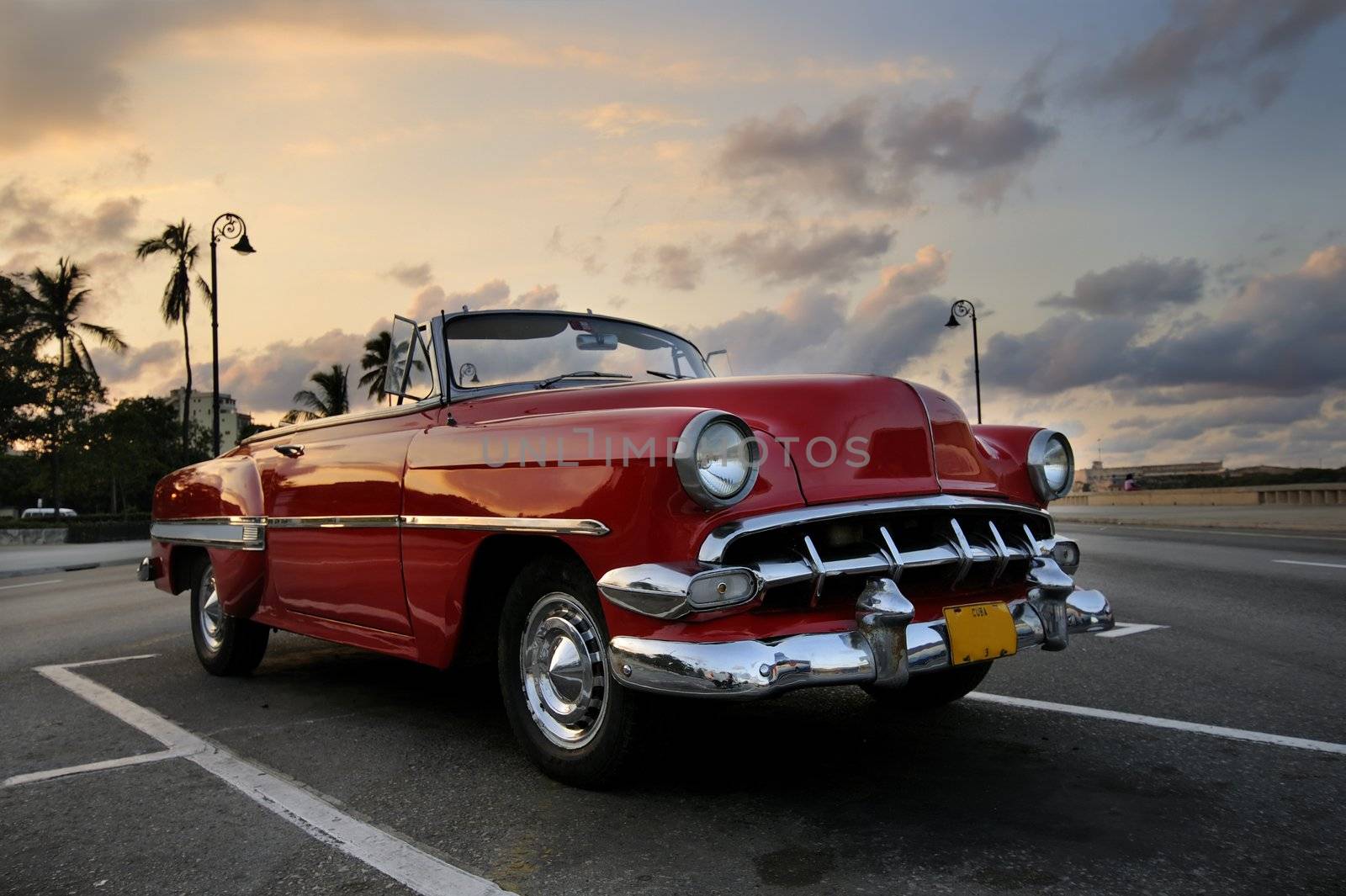 View of red classic vintage american car parked in havana street against sunset sky
