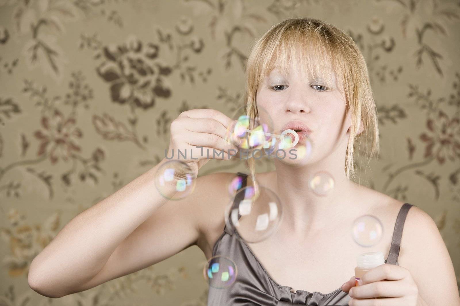 Pretty young girl with blue eyes blowing bubbles