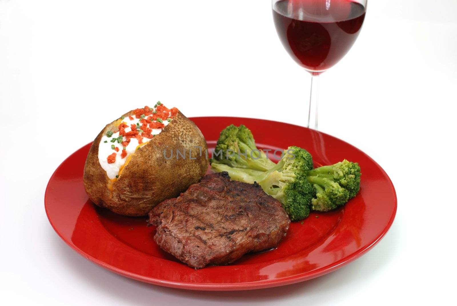 Grilled rib eye steak with baked potato and broccoli.  Isolated on white background.