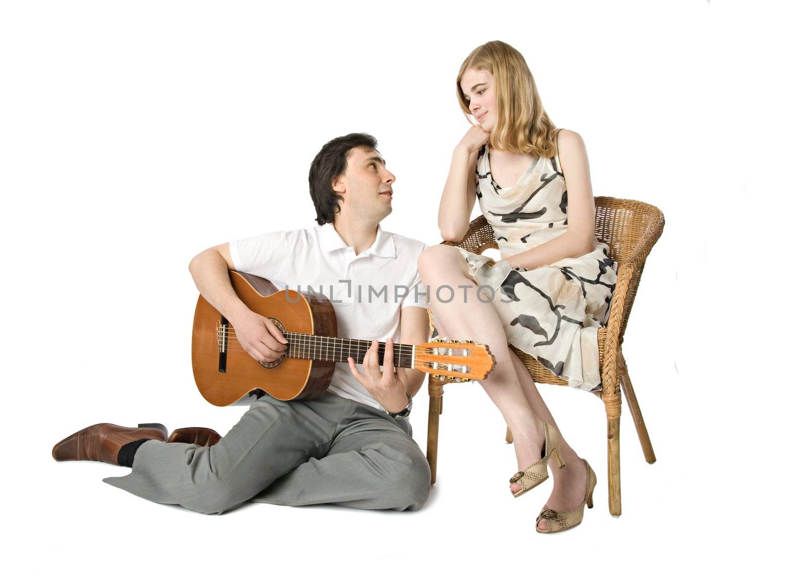 A blond girl and a man playing guitar for her