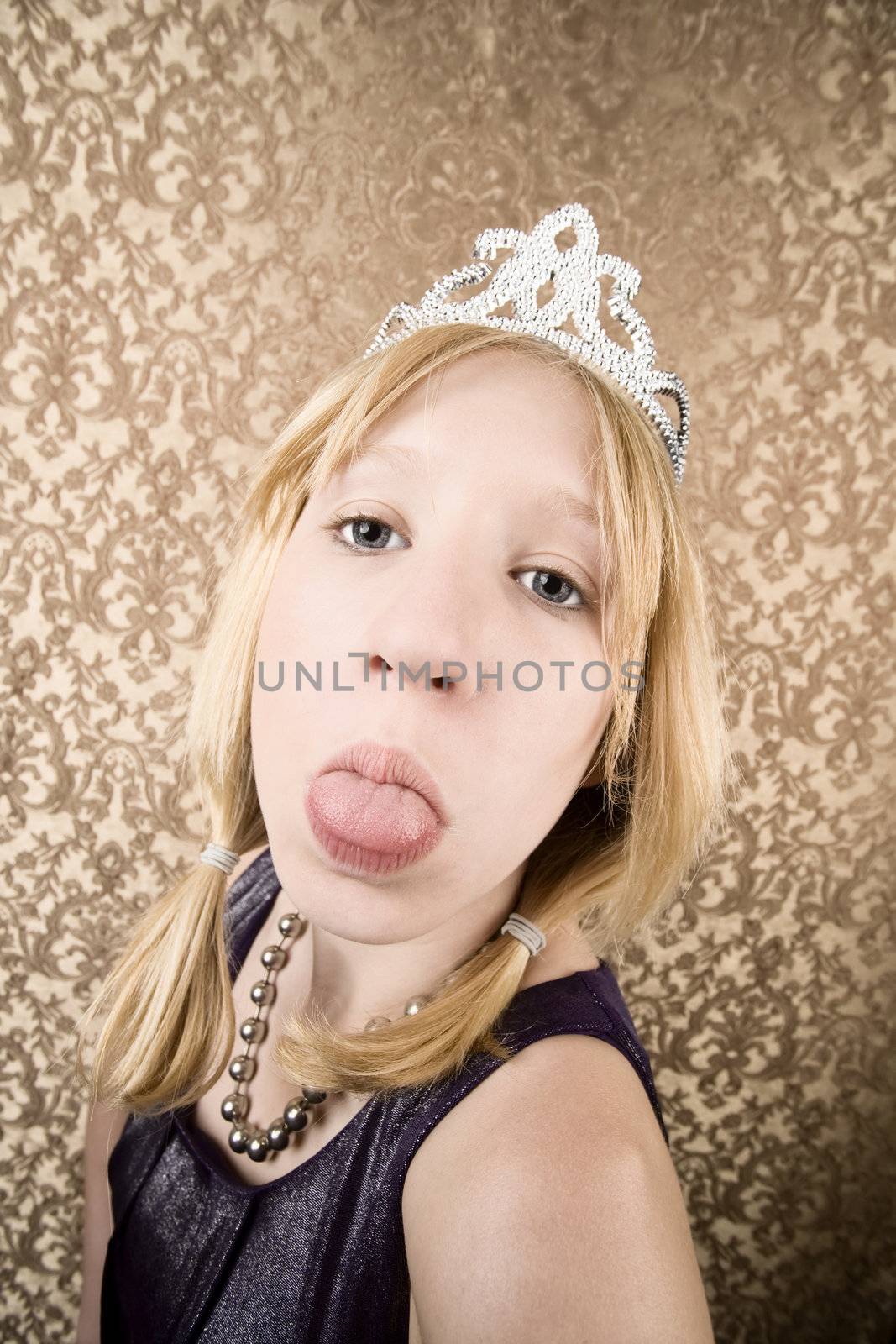 Portrait of pretty pouting young girl wearing a tiara with her tongue out