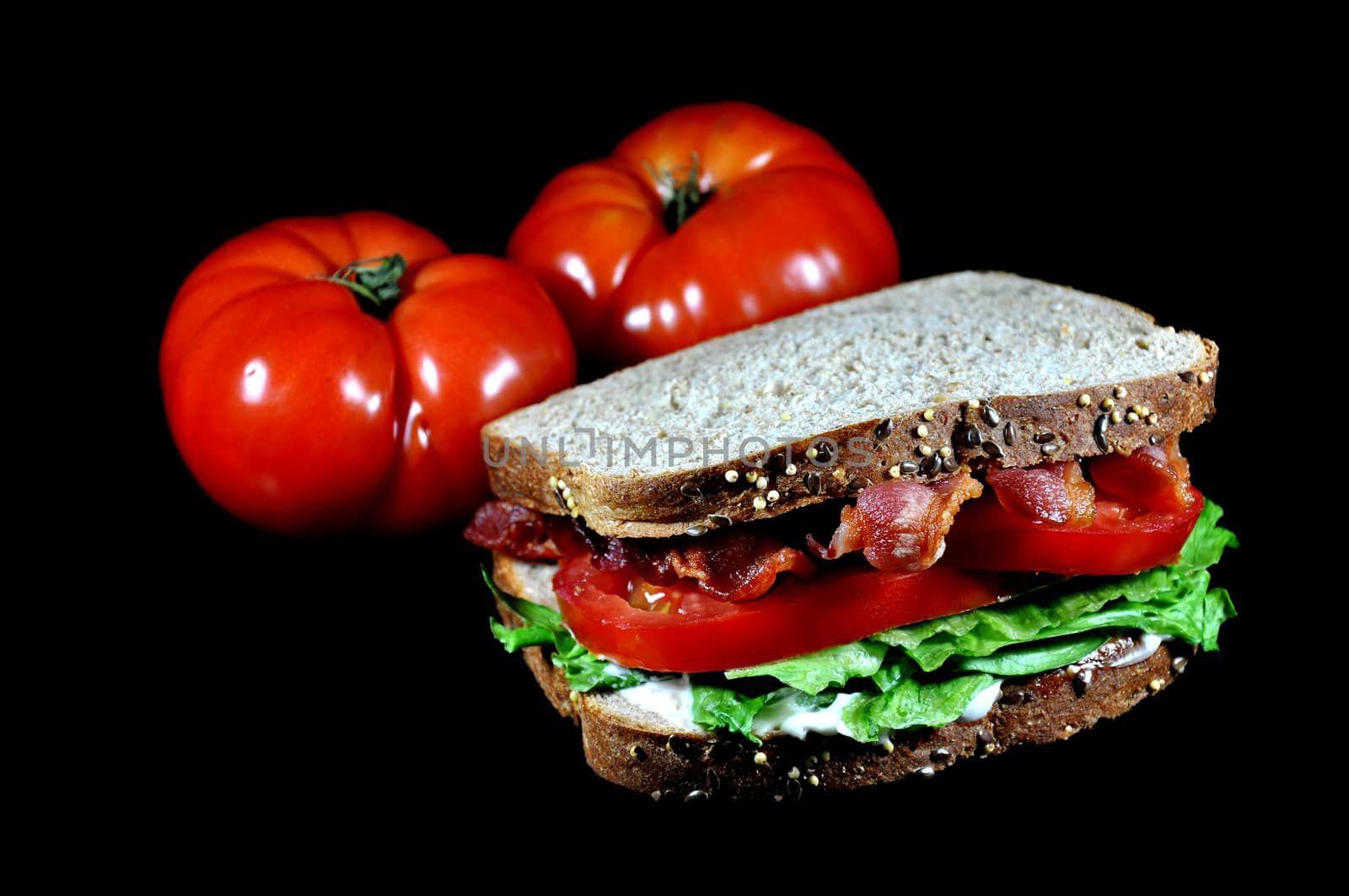 Bacon, lettuce, and tomato sandwich with tomatoes.  Isolated on black background.