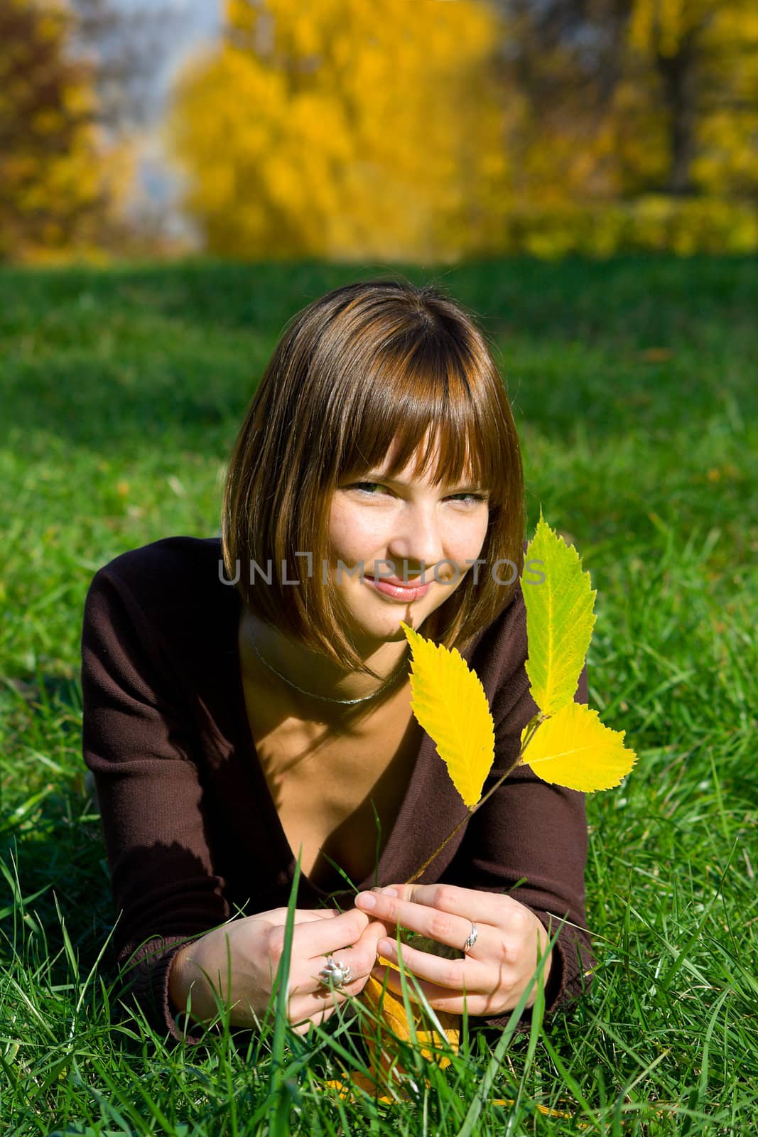 The young girl on green grass in autumn park