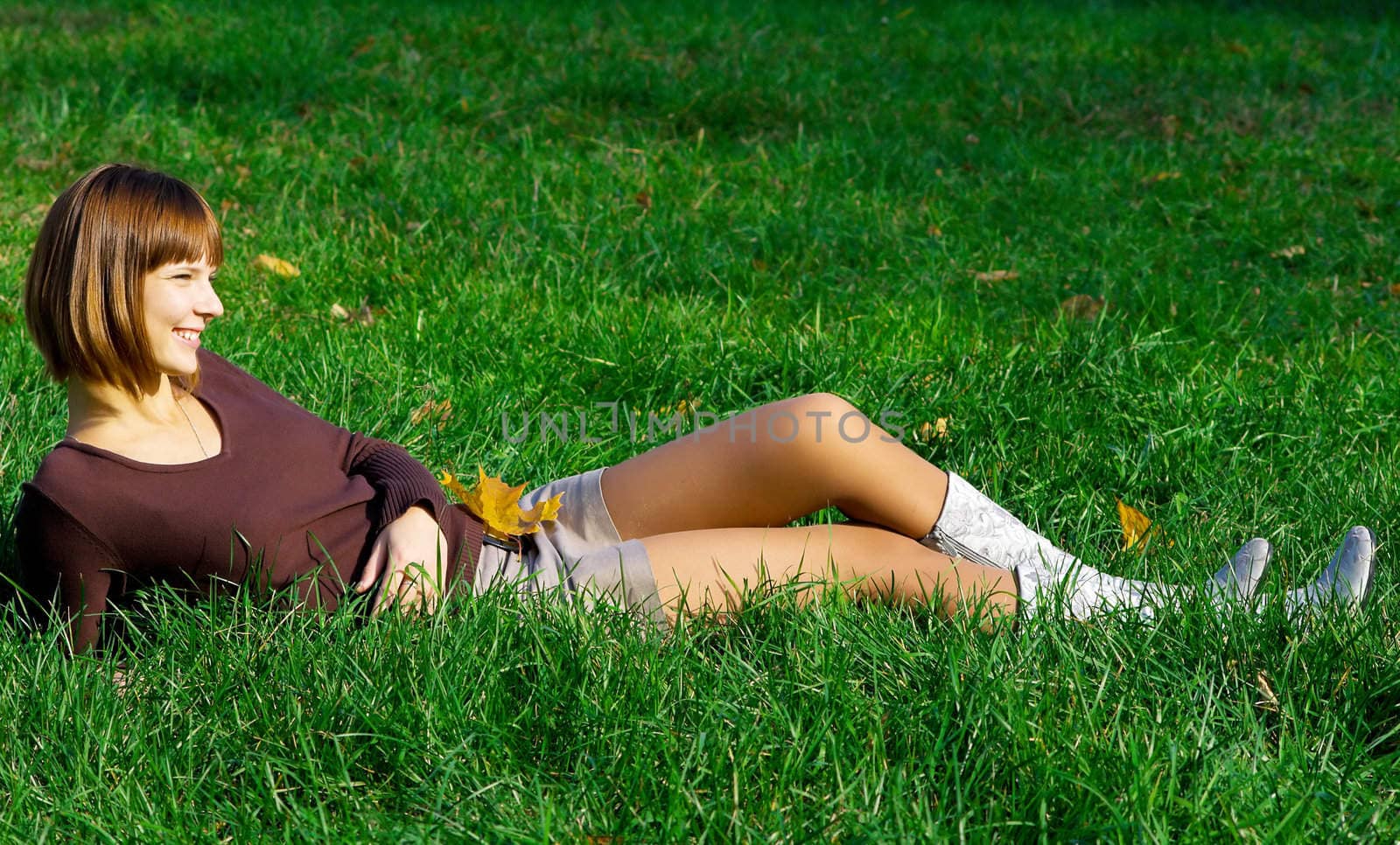 The young girl on green grass in autumn park