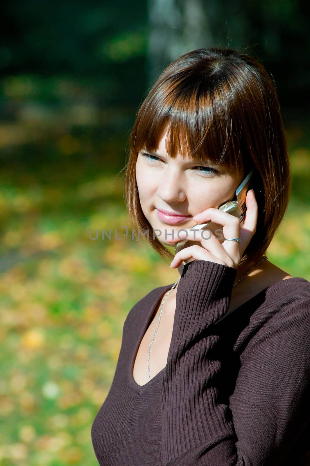 The young girl talks by a mobile phone. Outdoor