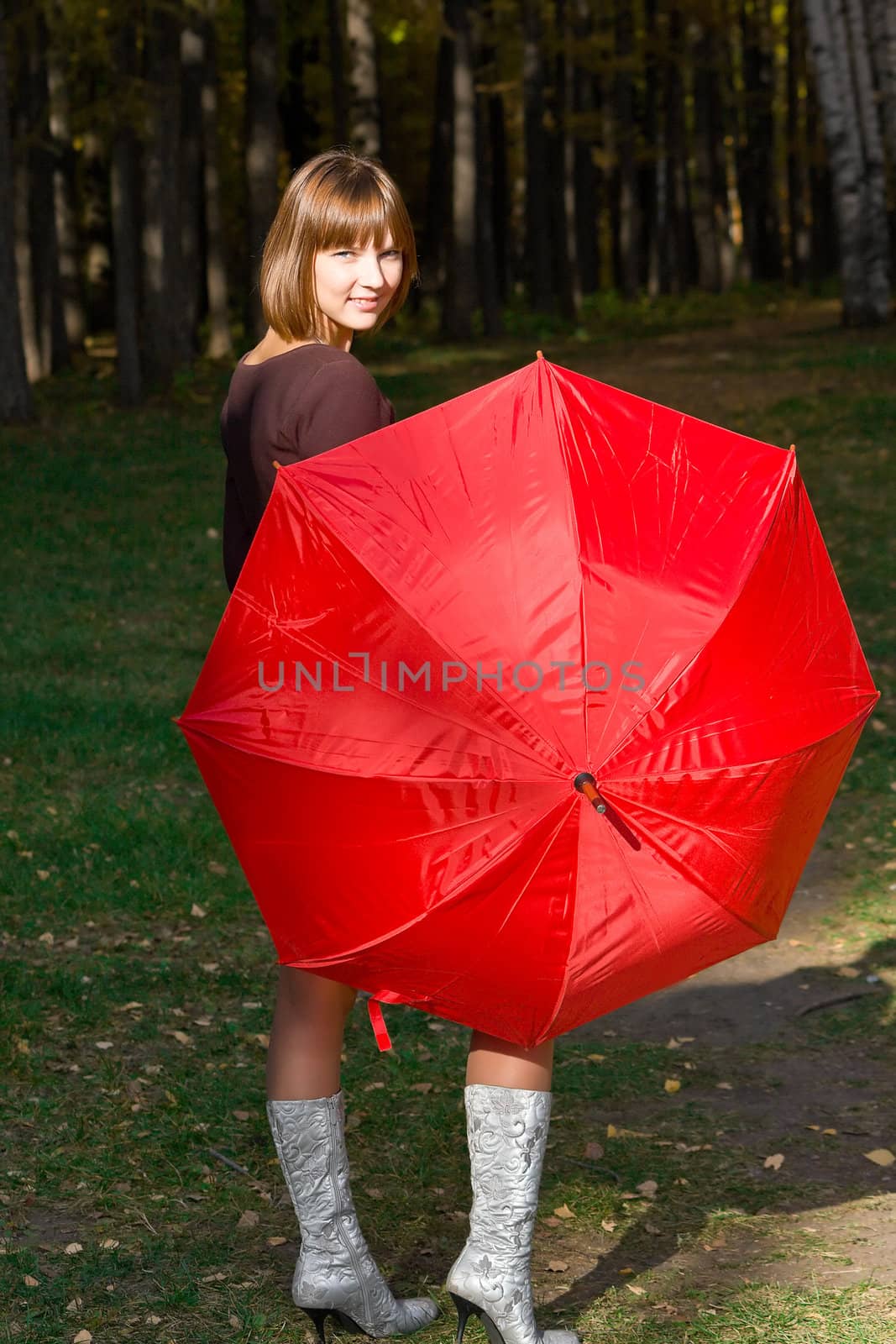 The young girl with a red umbrella in autumn park