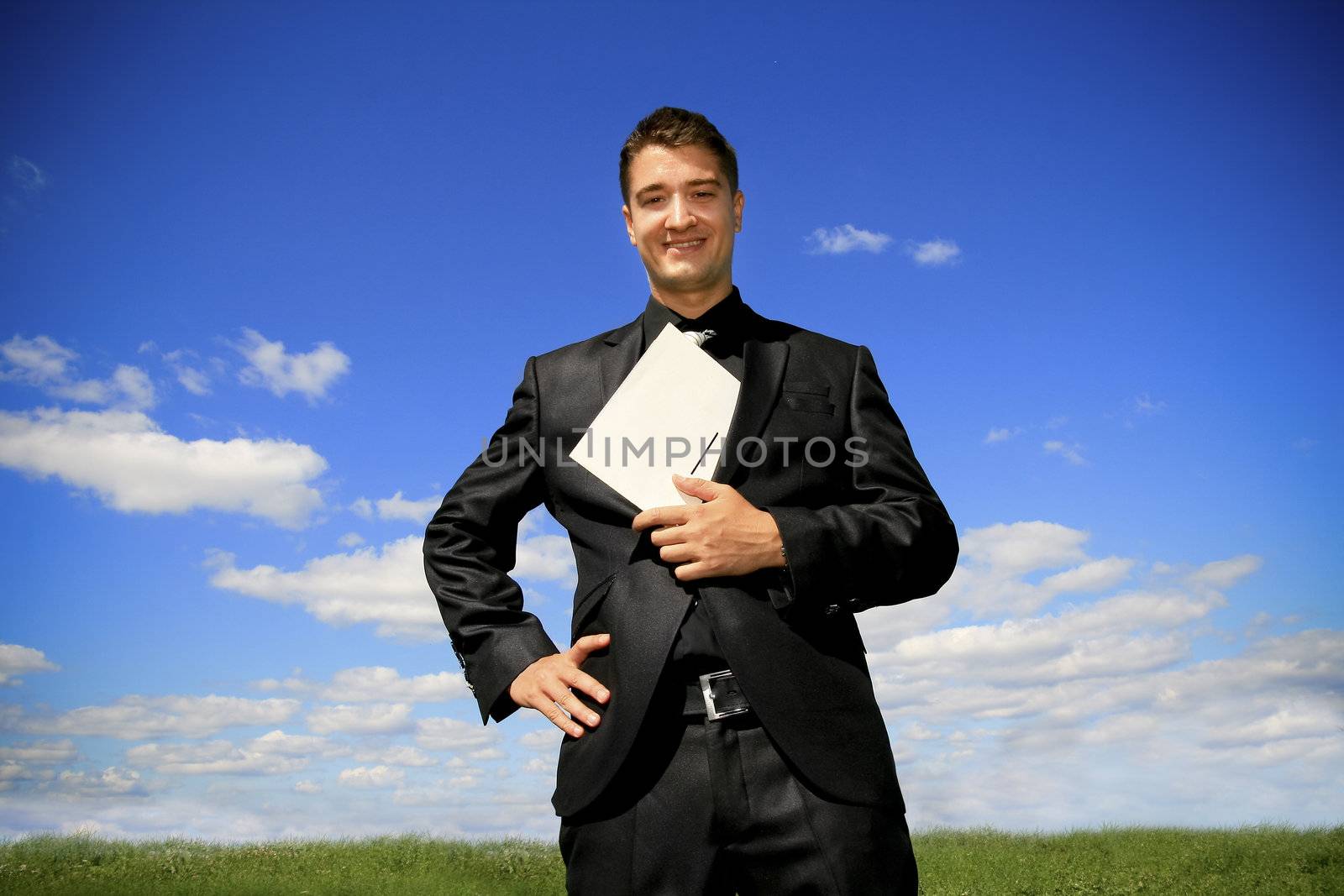 Young man in black suit in the middle of the field.