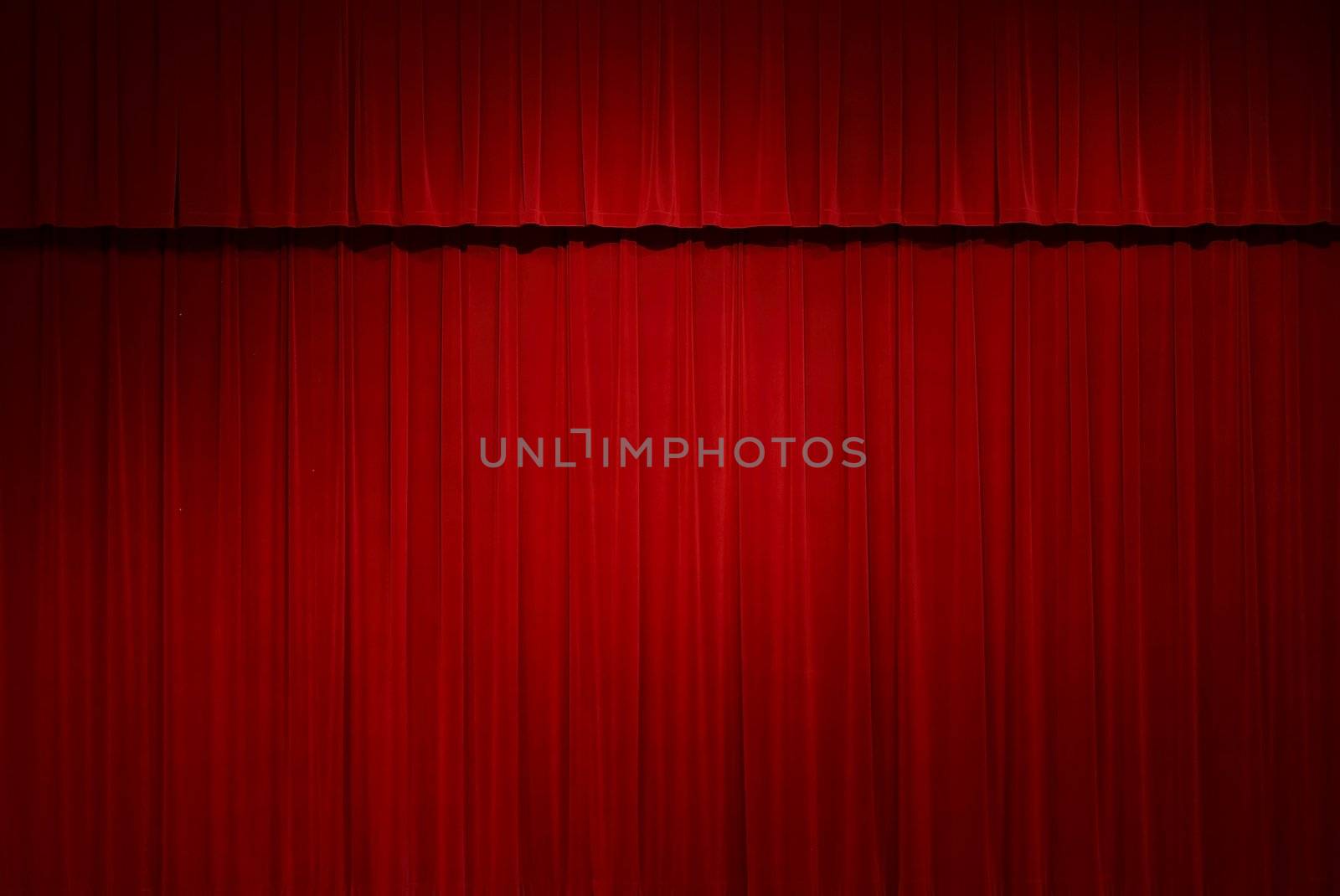 closed red stage curtains with a spot light on them
