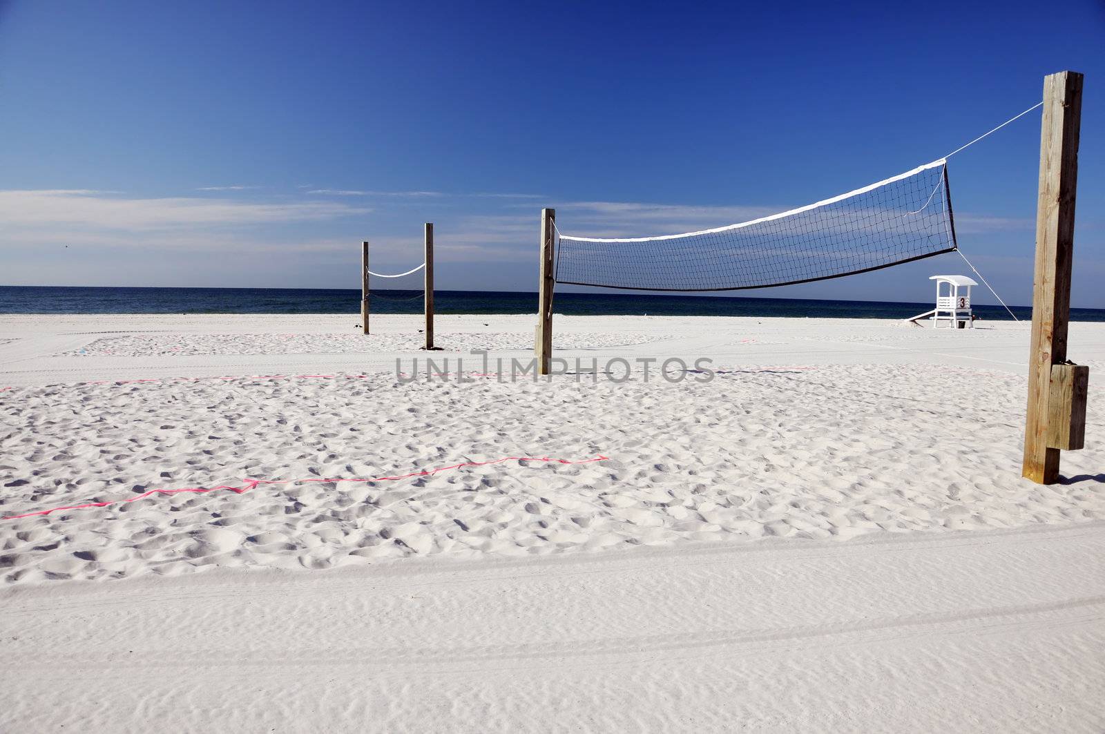 Beach volleyball nets with lifeguard hut in background.