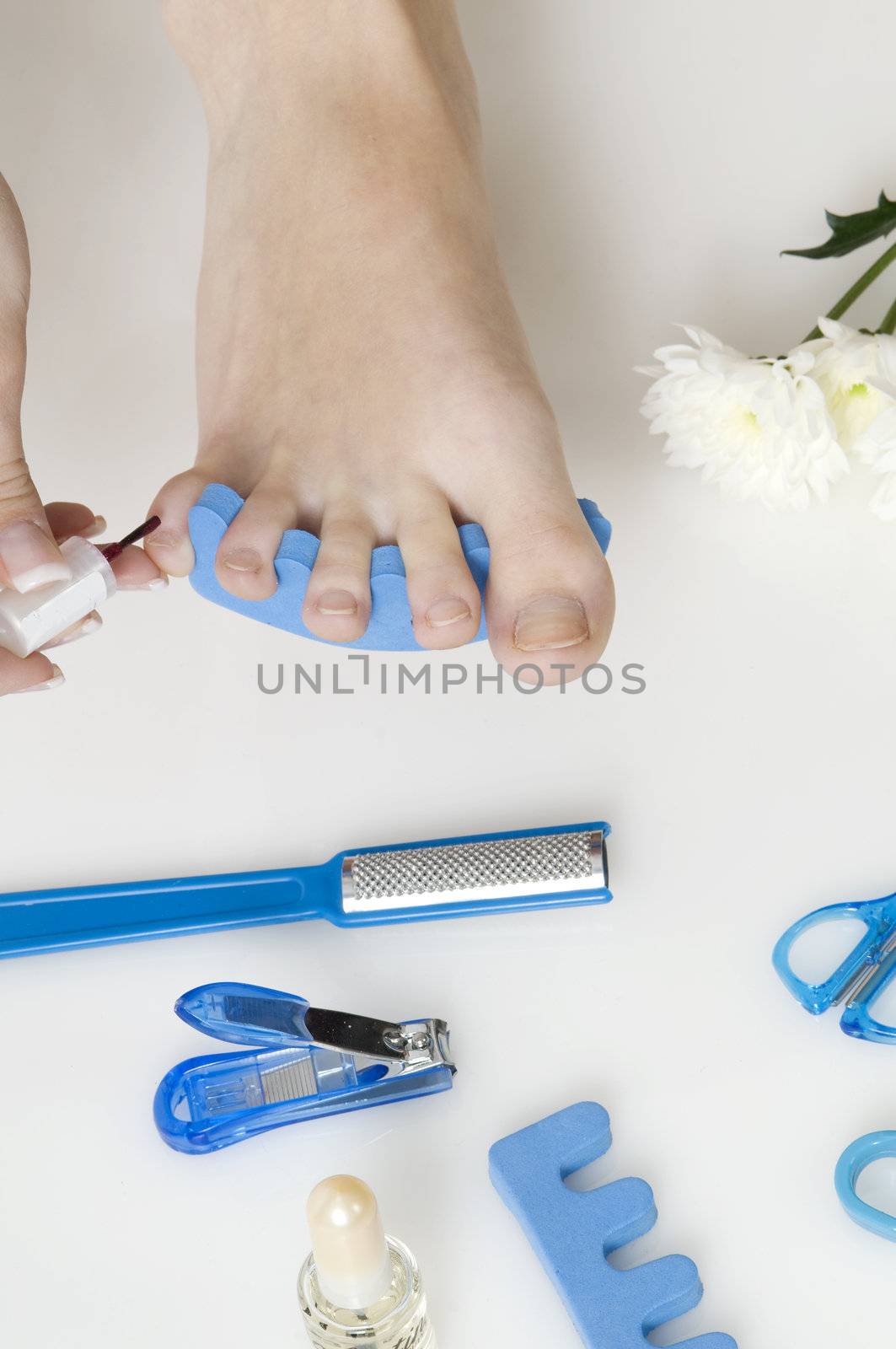 putting red varnish on foot nails with acessory in background