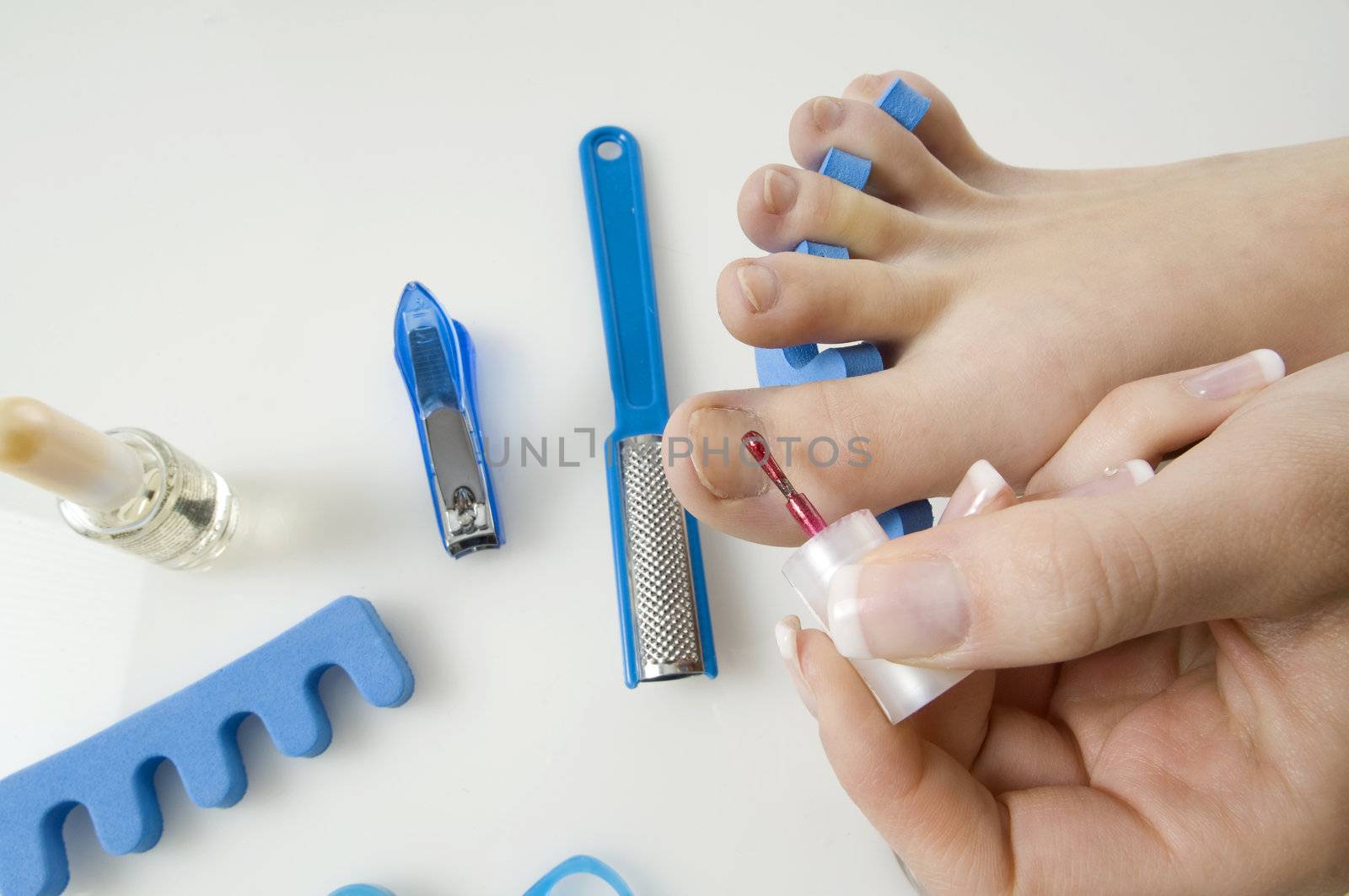 putting red varnish on foot nails with acessory in background