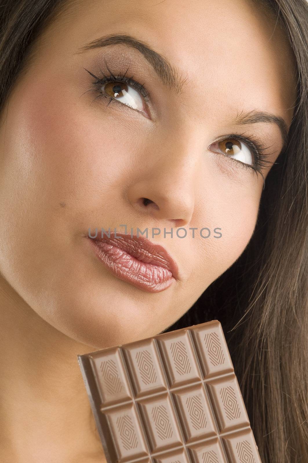 close up of a young and beautiful girl looking up and having a block of chocolate