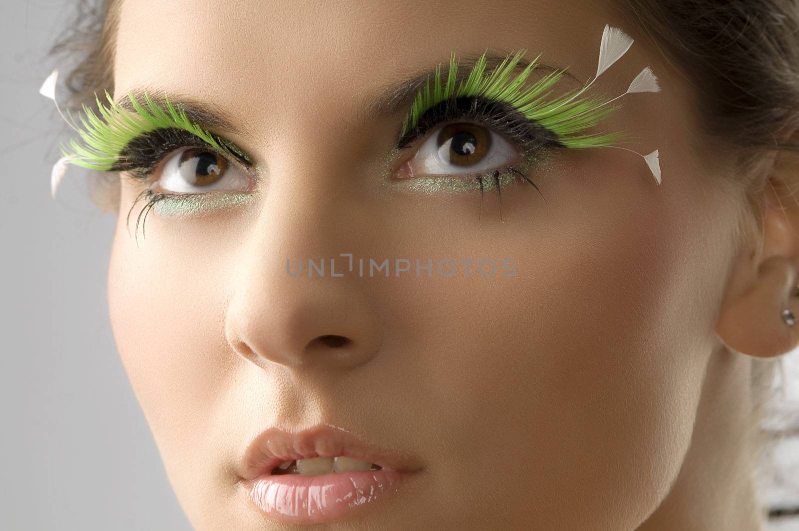 cute portrait of a young beautiful woman with artificial green eyelashes