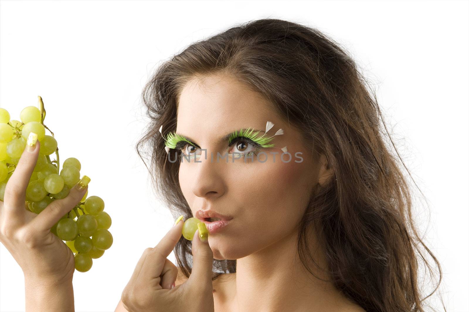 cute brunette with green artificial eyelashes eating a green grape
