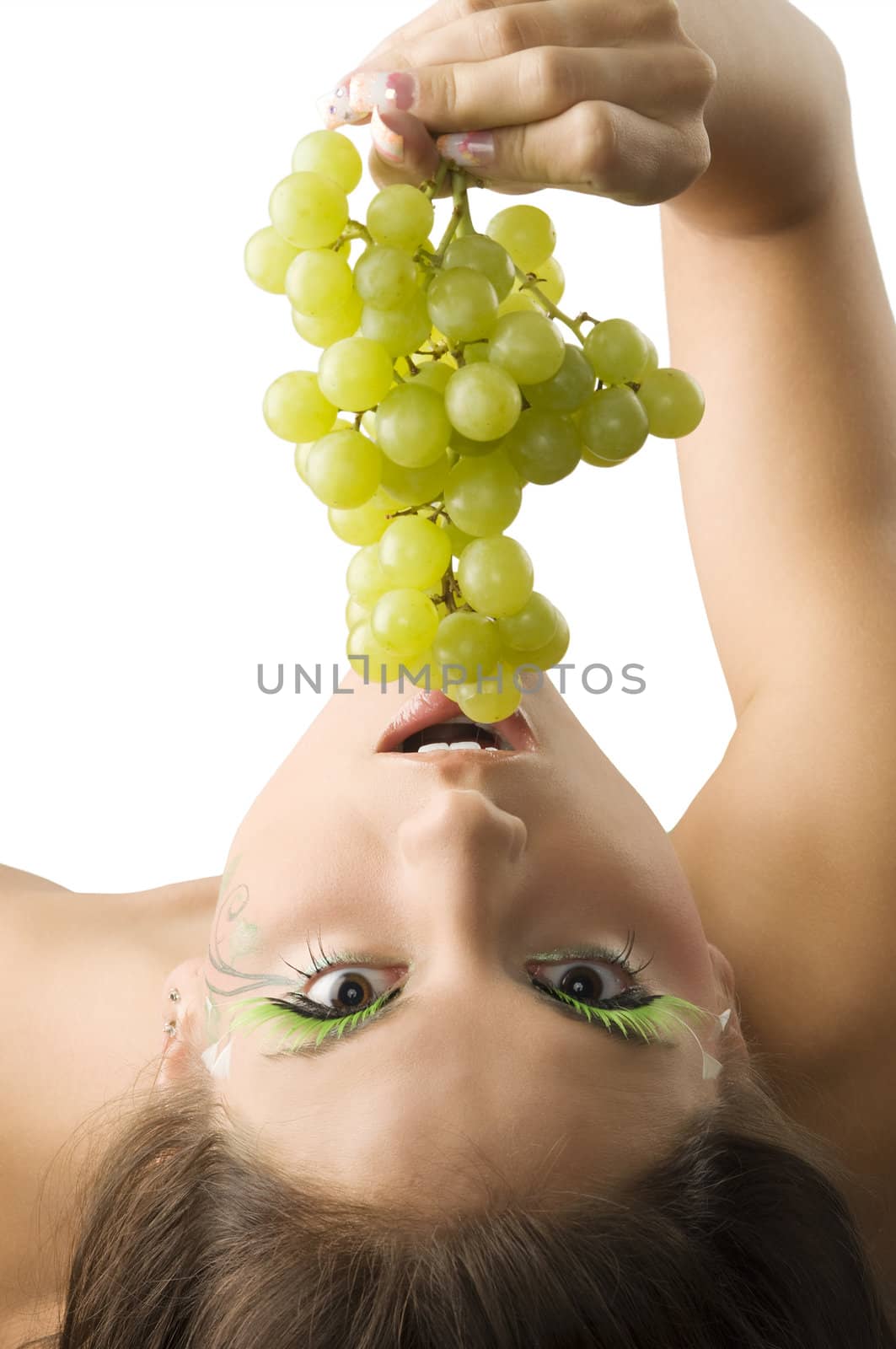 girl with her head down eating some green grape coming from top