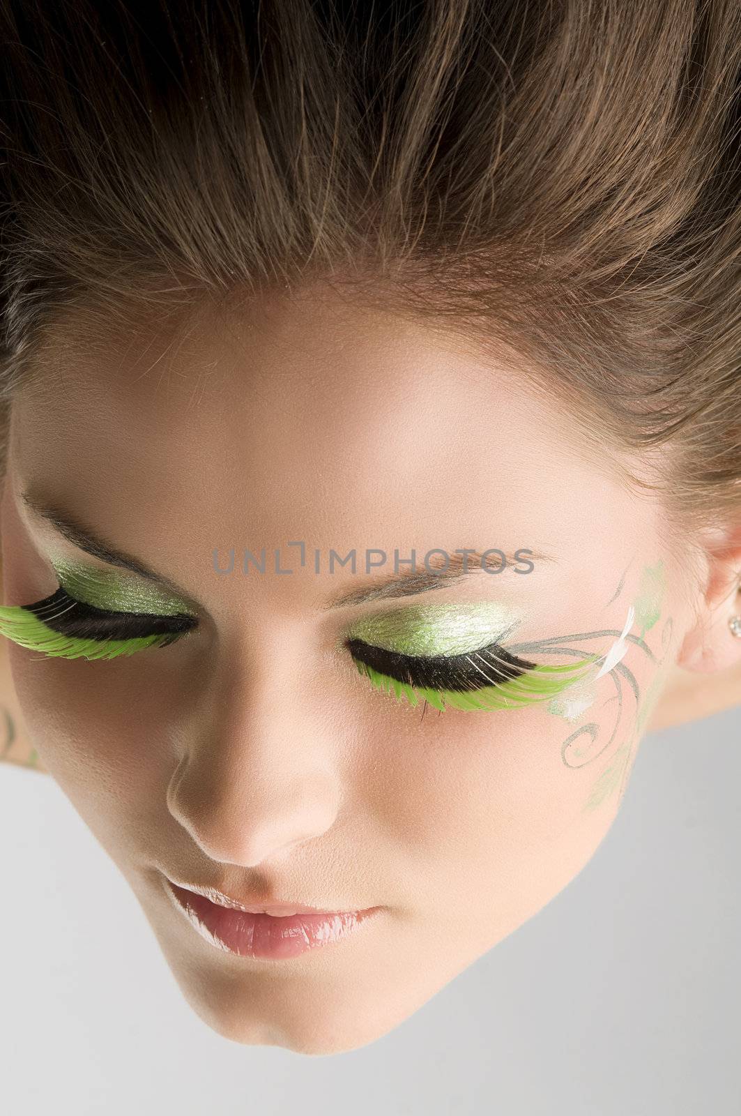 particular point of view of a face of a young brunette with green eyelashes