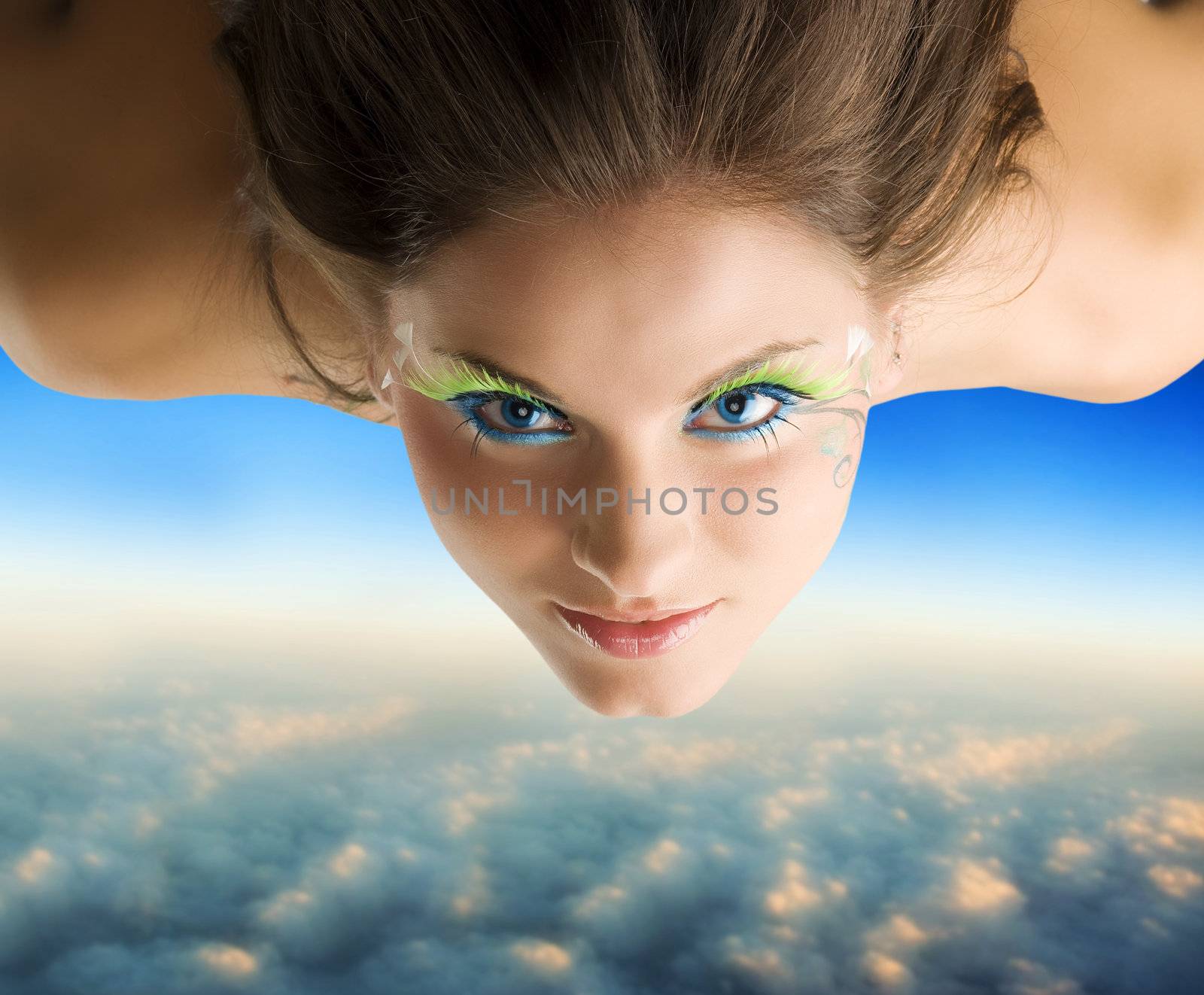 cute brunette with green eyelashes flying as a bird over the clouds