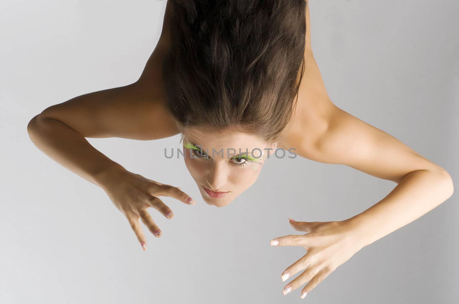 cute brunette with green eyelashes in act to be agressive moving hand like claw