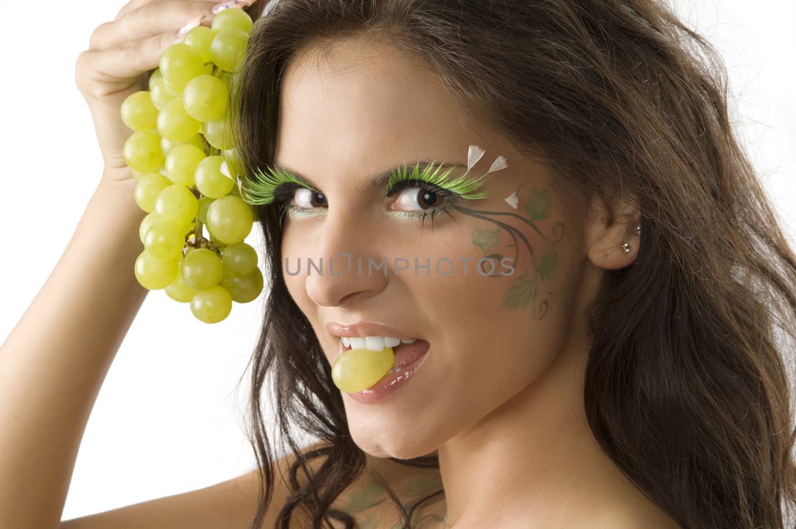 pretty girl with a grape between the teeth and her face painted with green leaf