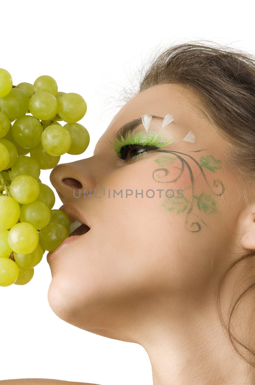 nice and sexy girl with a nice paint on her face in act to eat some green grape