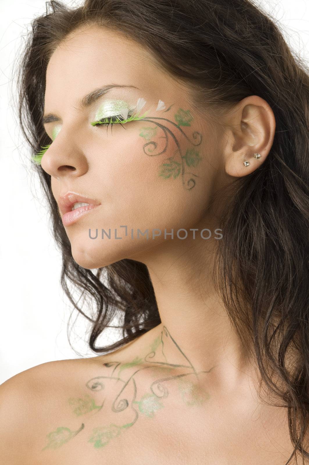 beautiful girl with body paint on her face and shoulder keeping her eyes closed