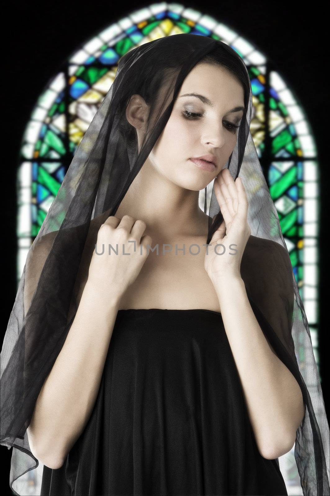 beautiful woman with a black veil on her head in a church like a madonna