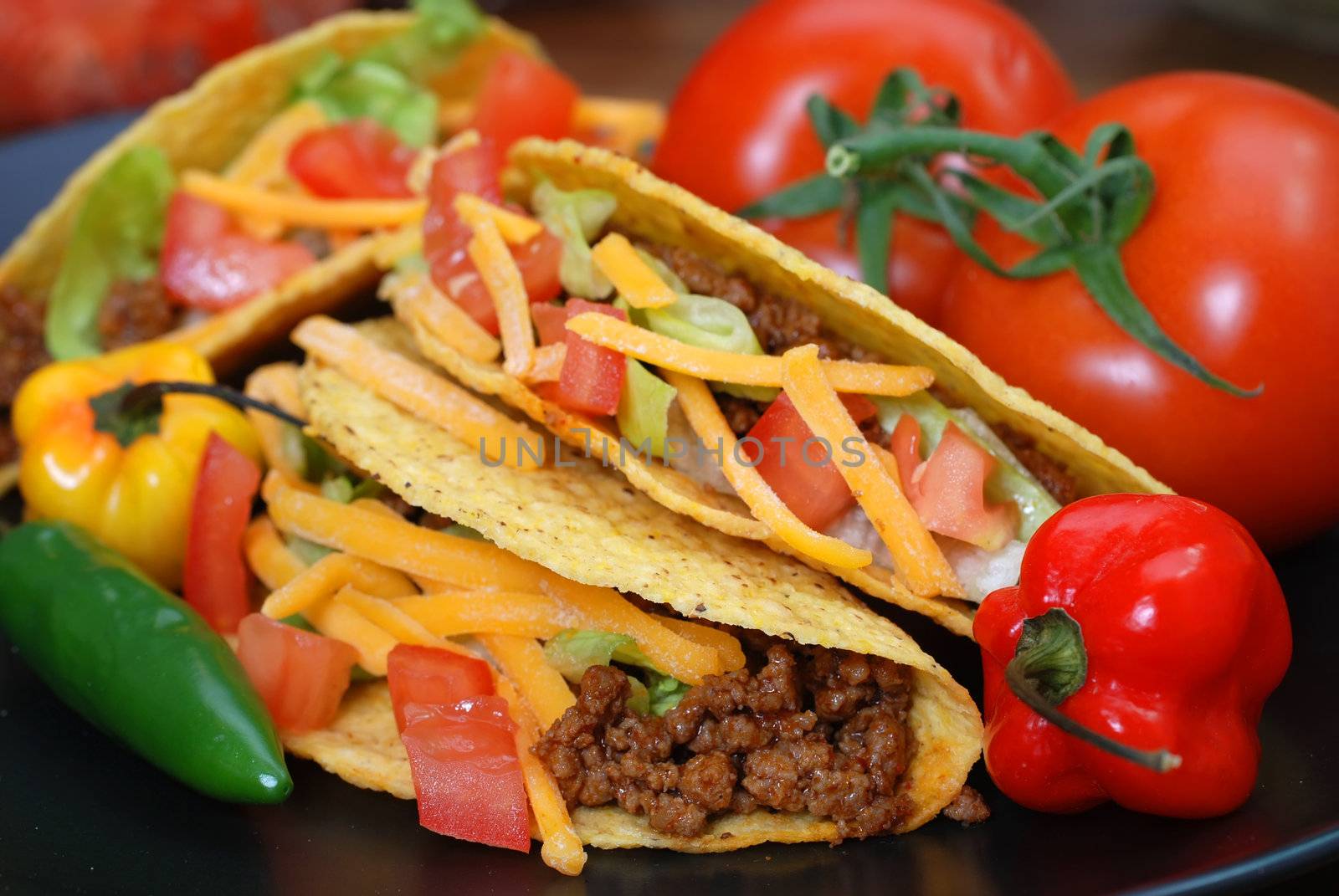 Closeup of tacos on plate with tomatoes, habanero and serano peppers.
