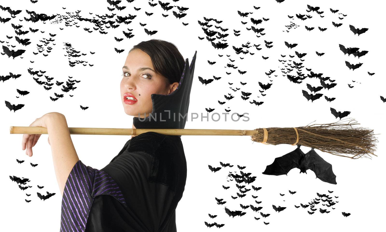 pretty witch in black dress with her broom on shoulder and black bat flying