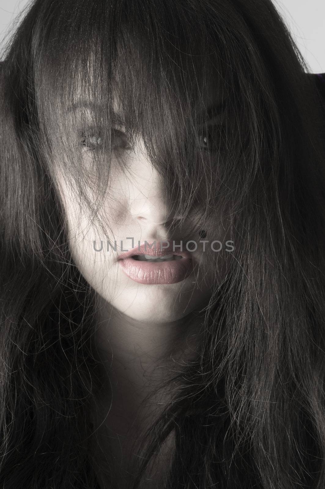 cute brunette with long hair on her face in a desaturated portrait