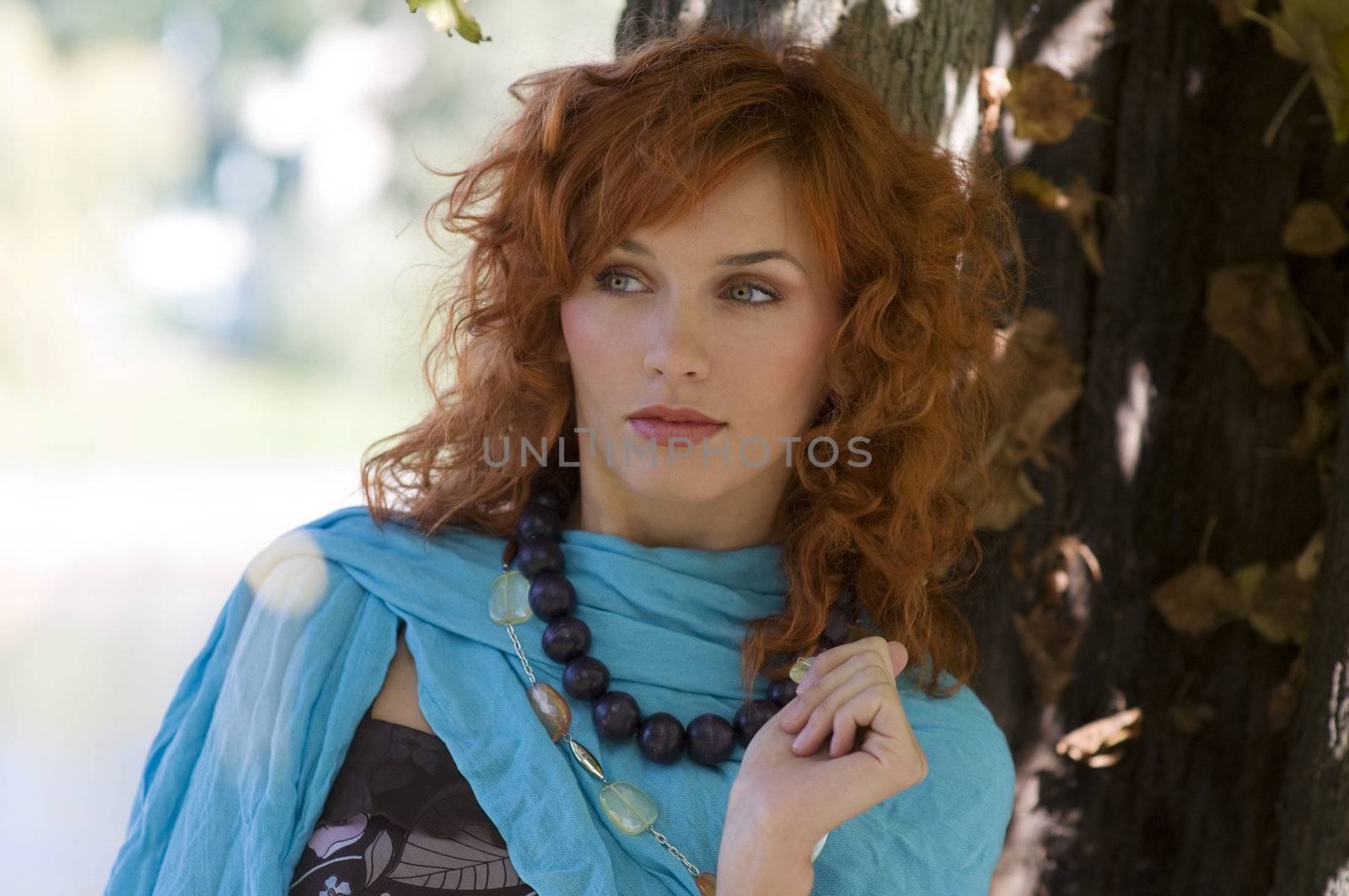 red haired girl in autumn forest with necklace looking curios