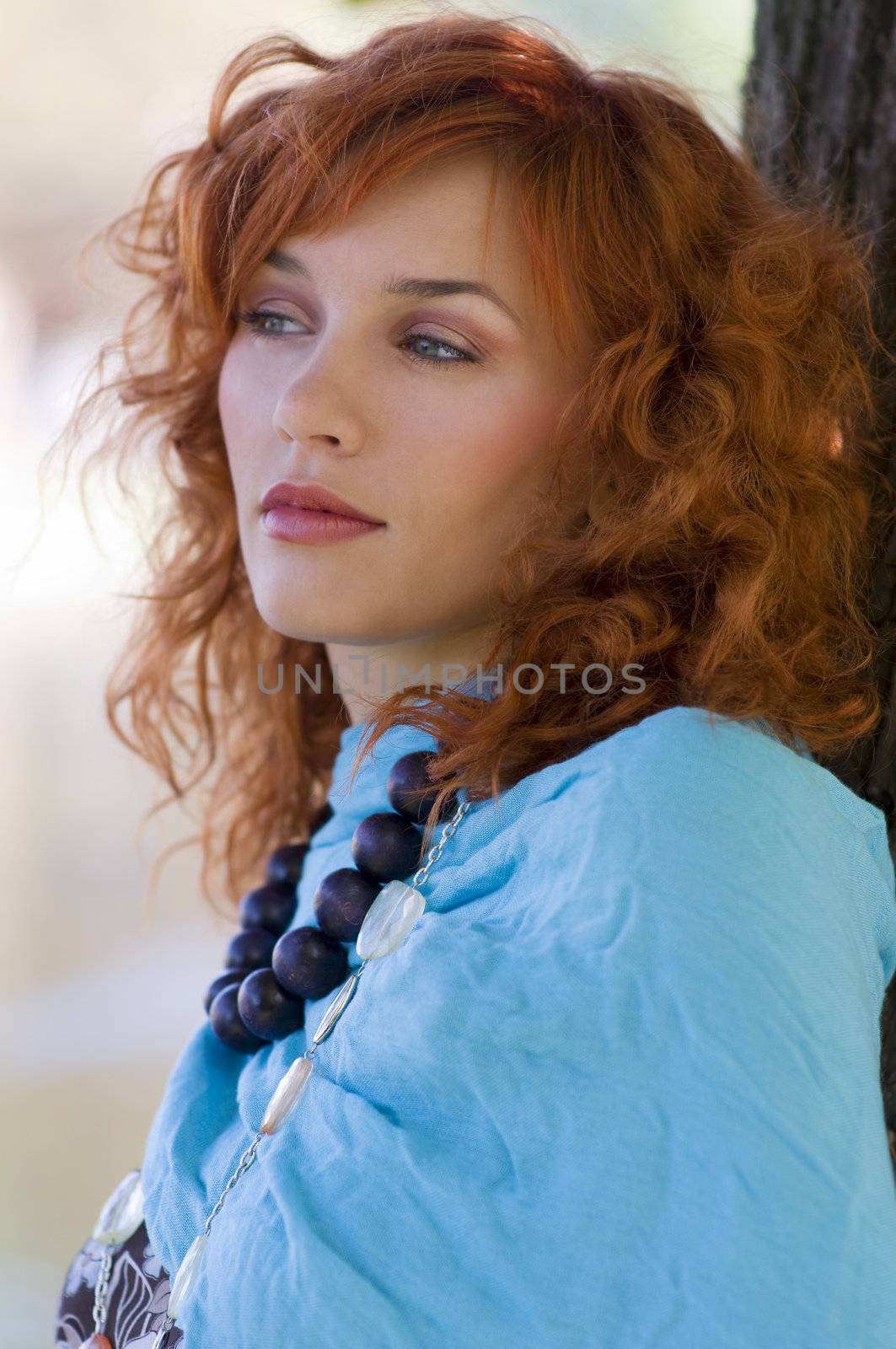 portrait in the park of a red haired girl with a blue scarf and necklace