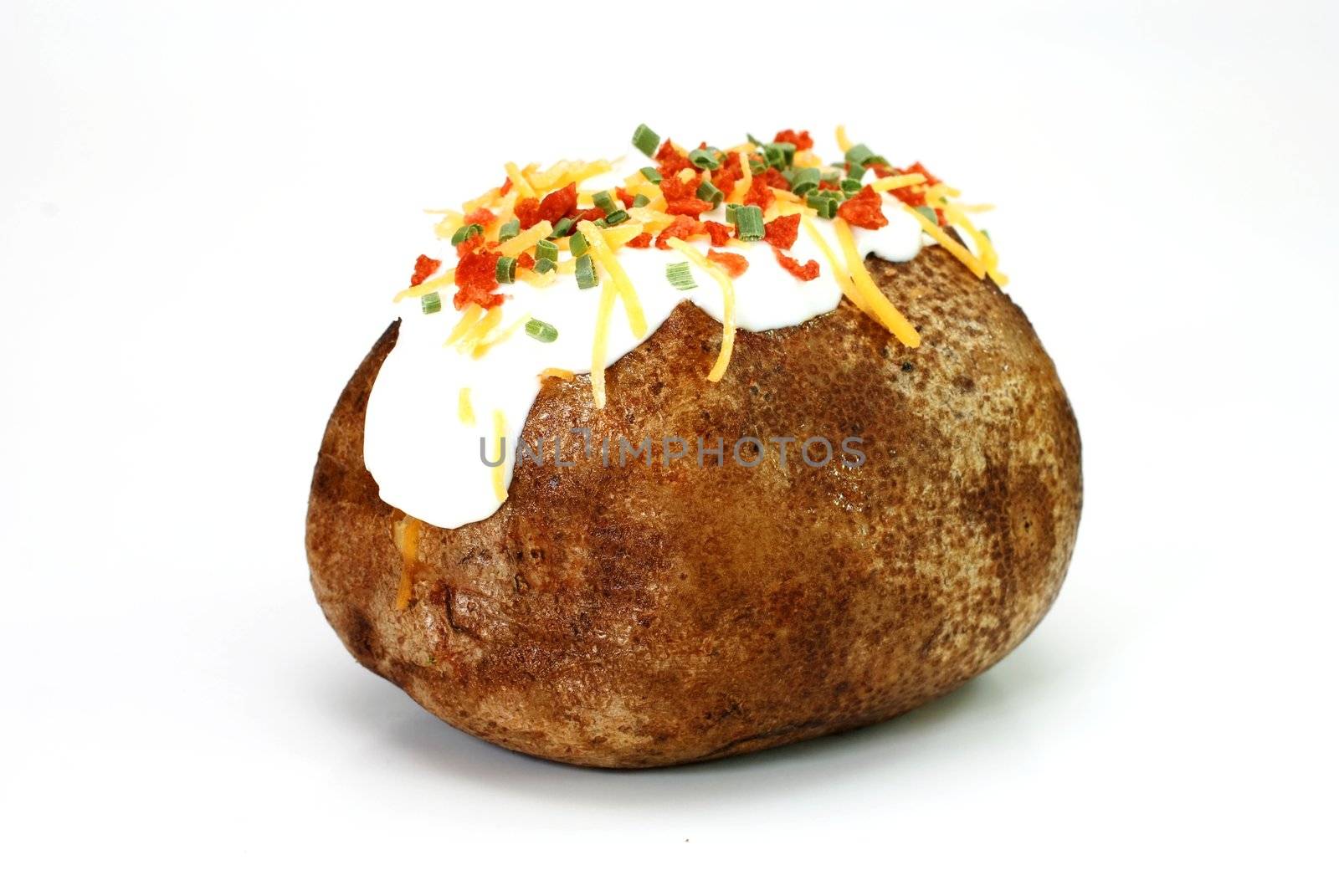 Baked potato loaded with butter, sour cream, cheddar cheese, bacon bits, and chives.  Isolated on white background.