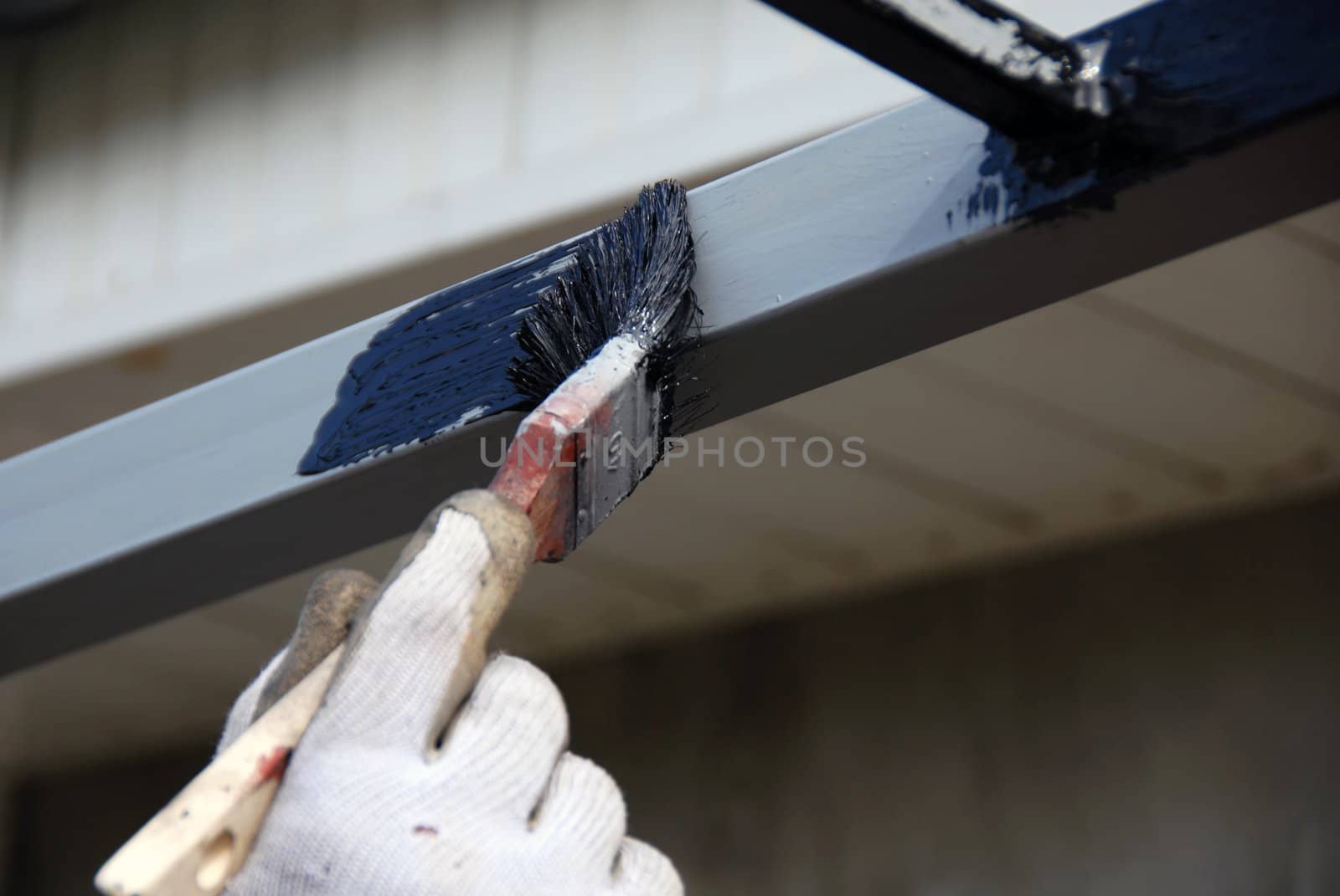 painting brush on metal rod with black paint closeup
