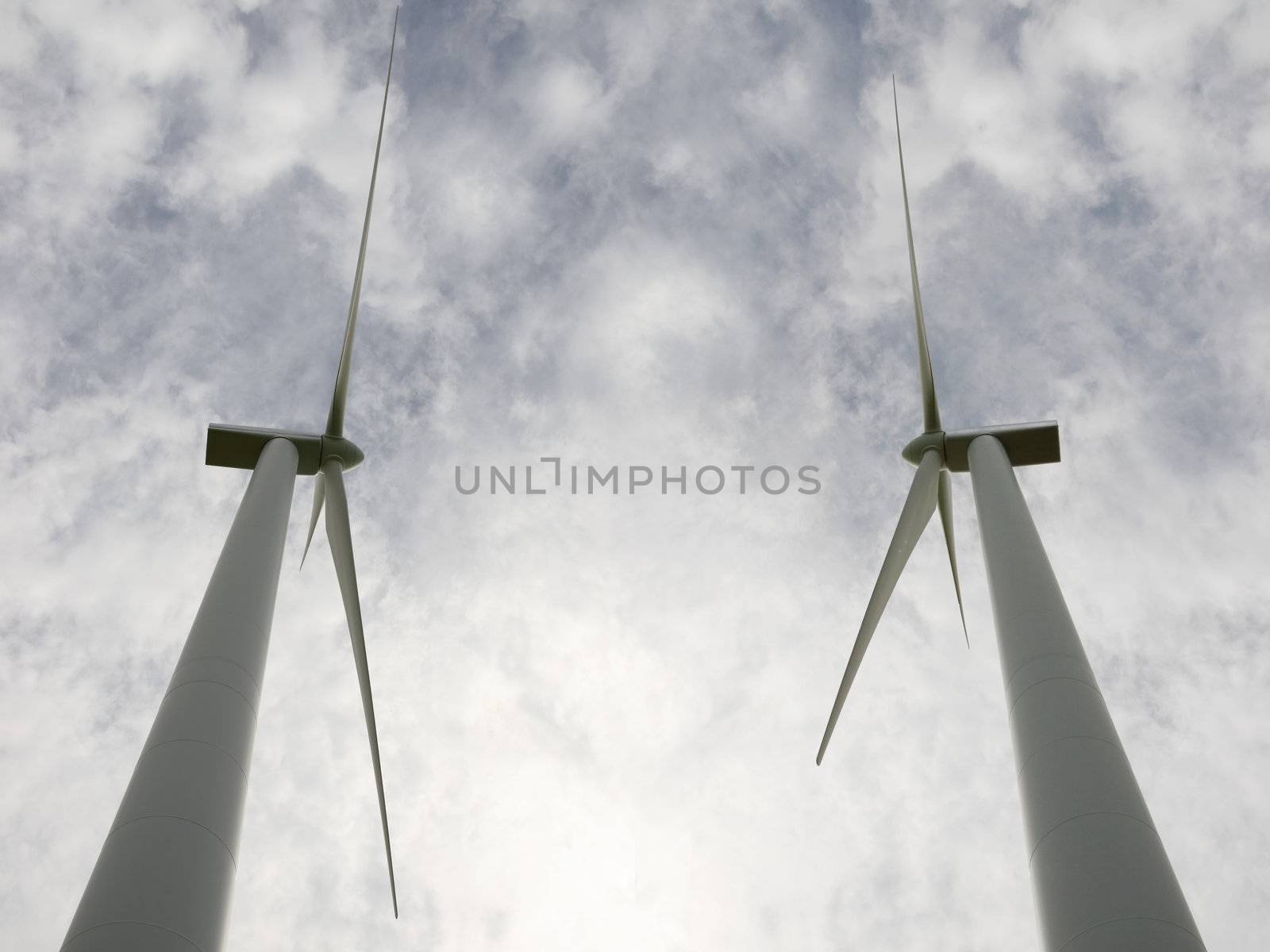 two wind turbine against a calm cloudy sky side by side