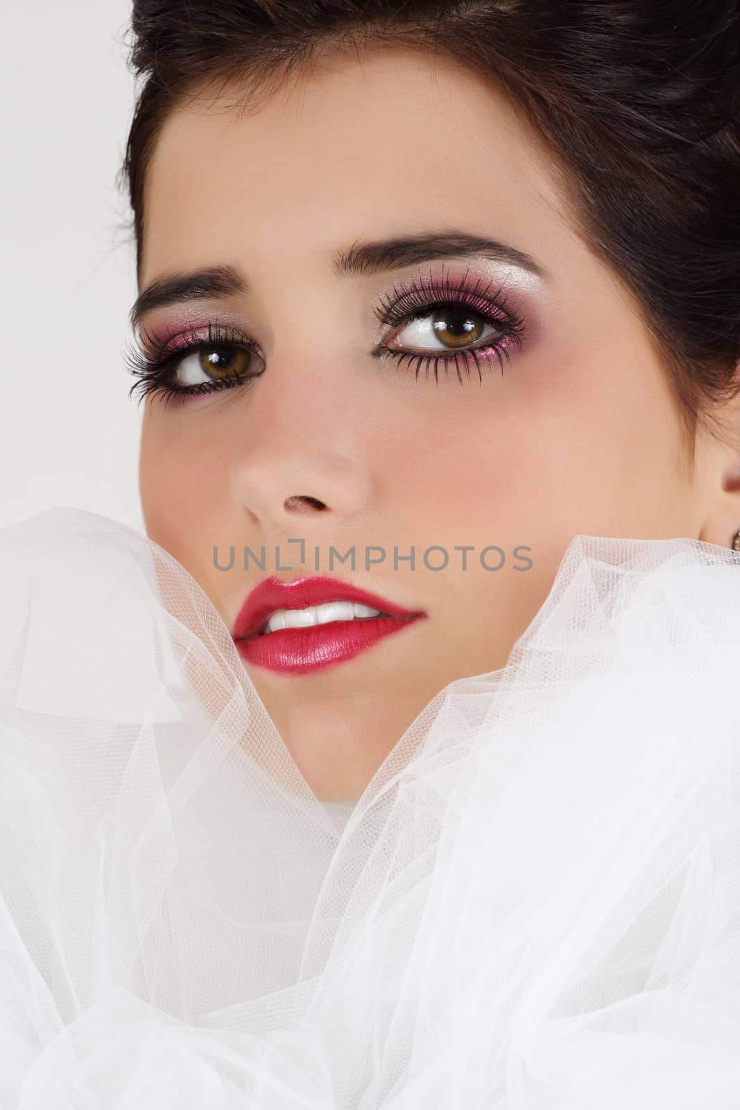 Closeup portrait of a beautiful young woman, white background with white tulle