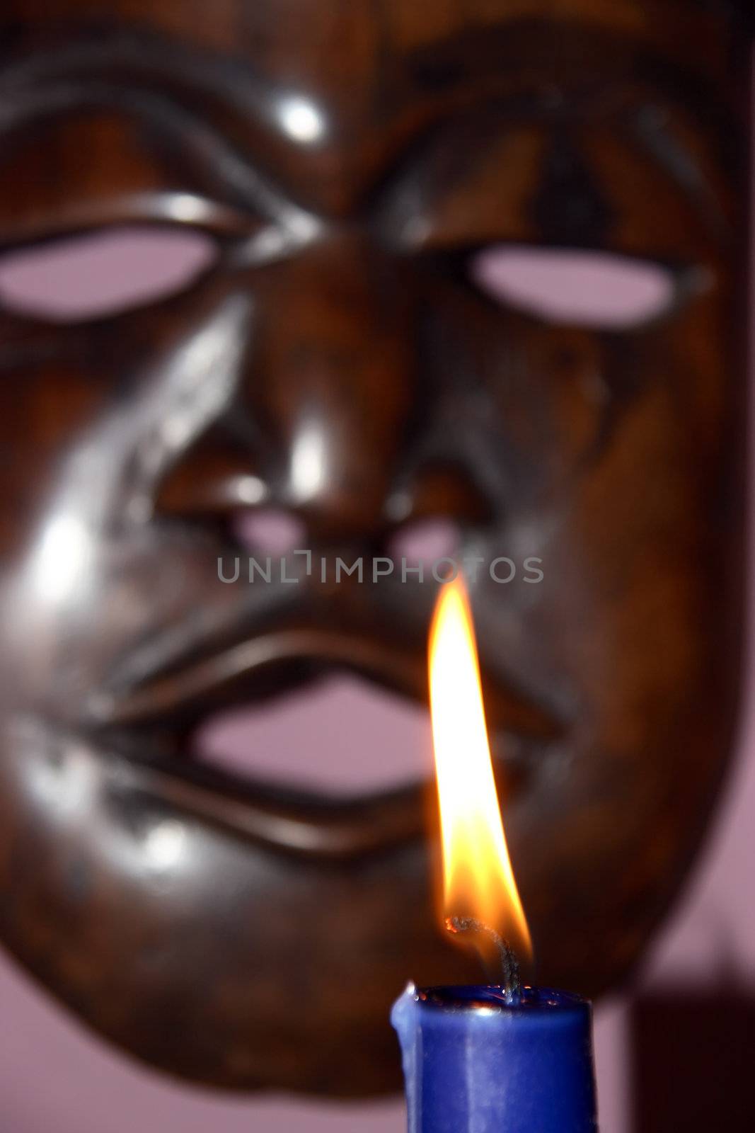 an african mask with a candle burning in the foreground