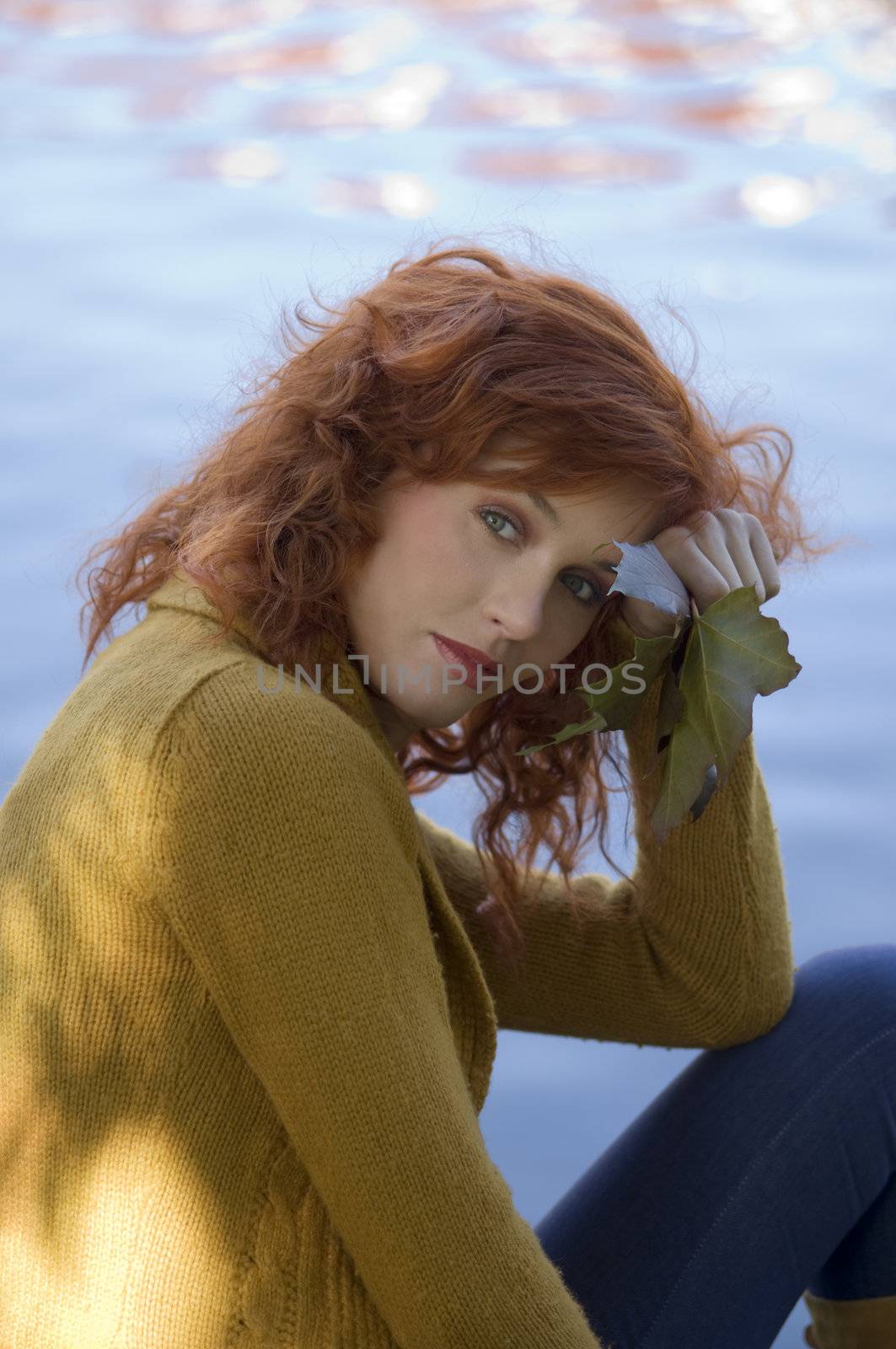 romantic autumn portrait of a red haired woman near a river