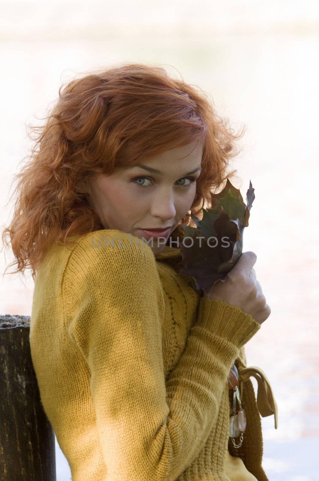pretty close up of red-haired woman playing with leaf outdoor