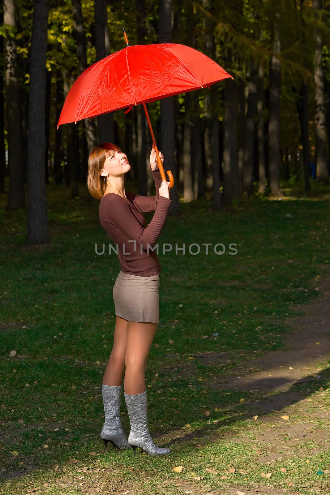 The young girl with a red umbrella in autumn park