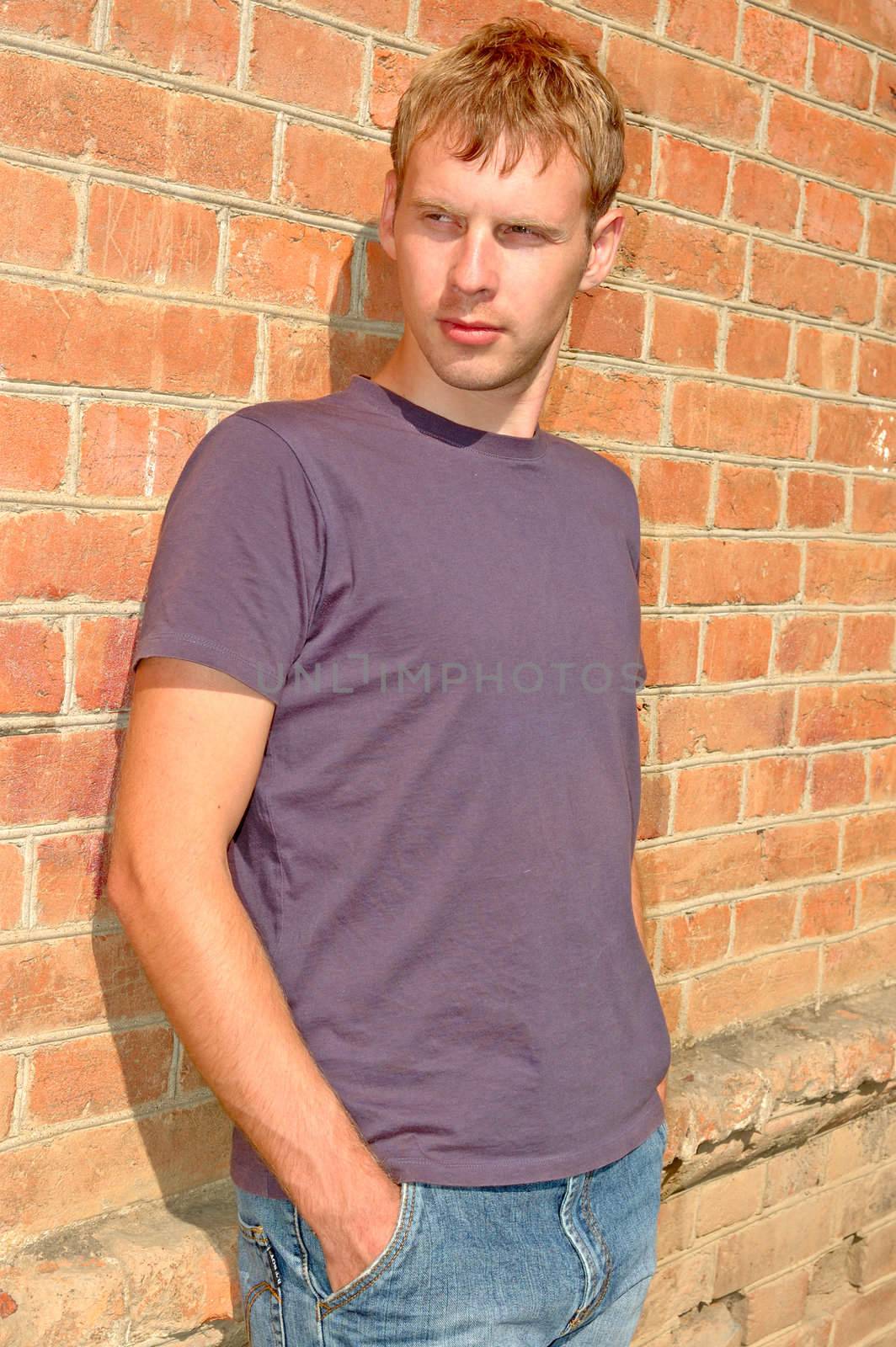 Young stylish man stand near brick wall. by alexpurs