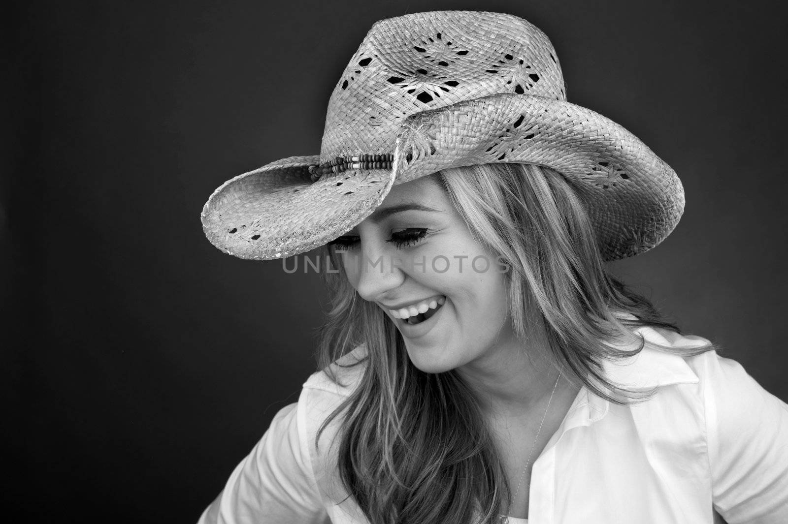 B&W image of a beautiful cowgirl laughing wearing cowboy hat