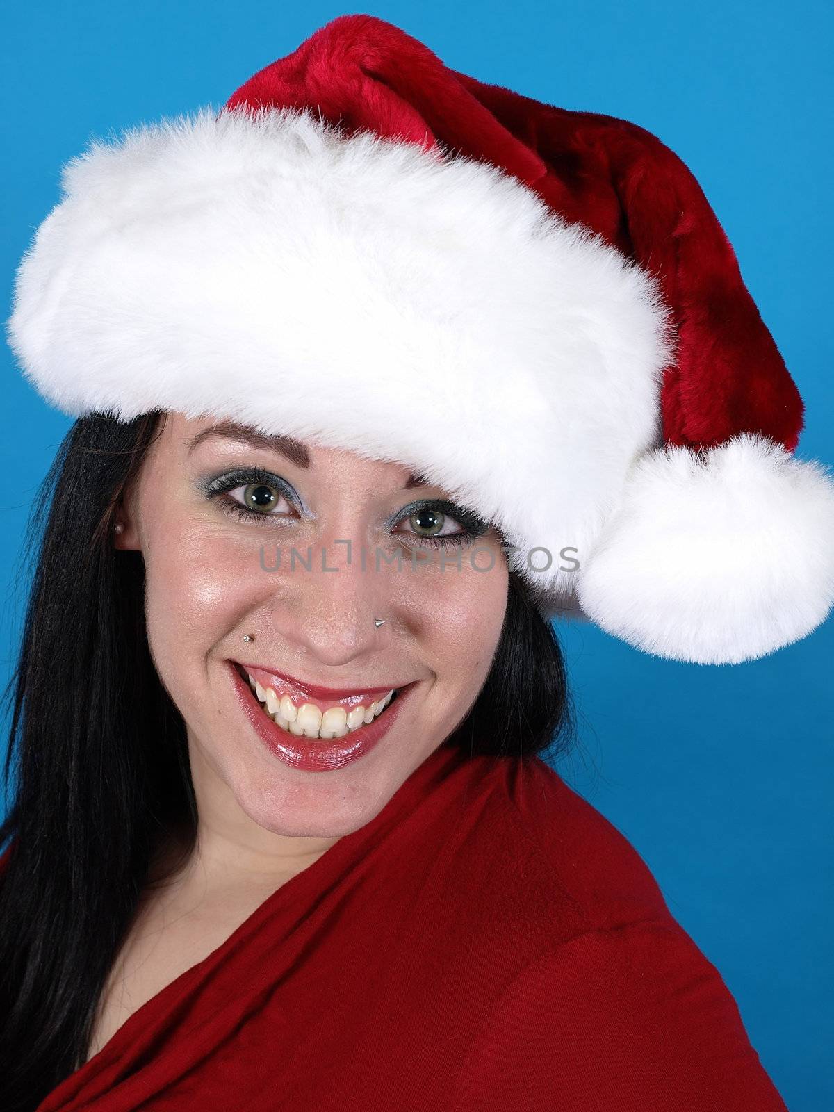 A pretty young pierced adult woman in a Santa hat cheerfully smiles.