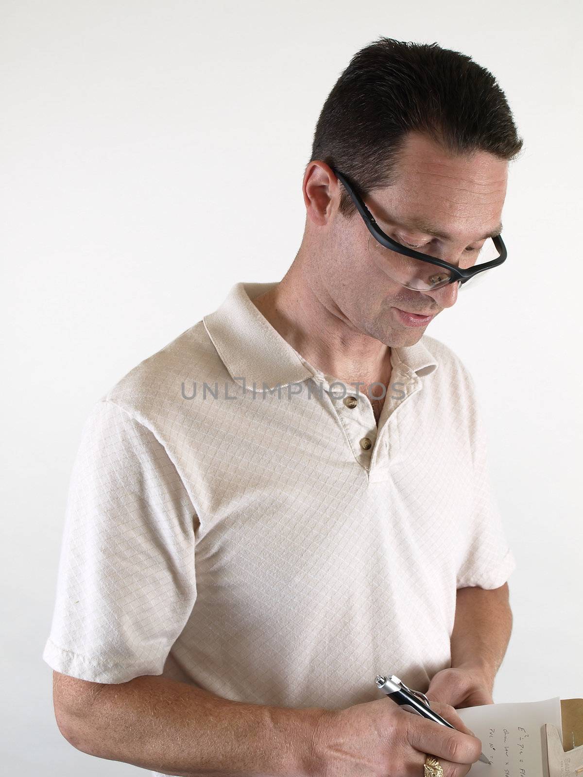 A male wearing safety glasses writes a note on a clipboard.
