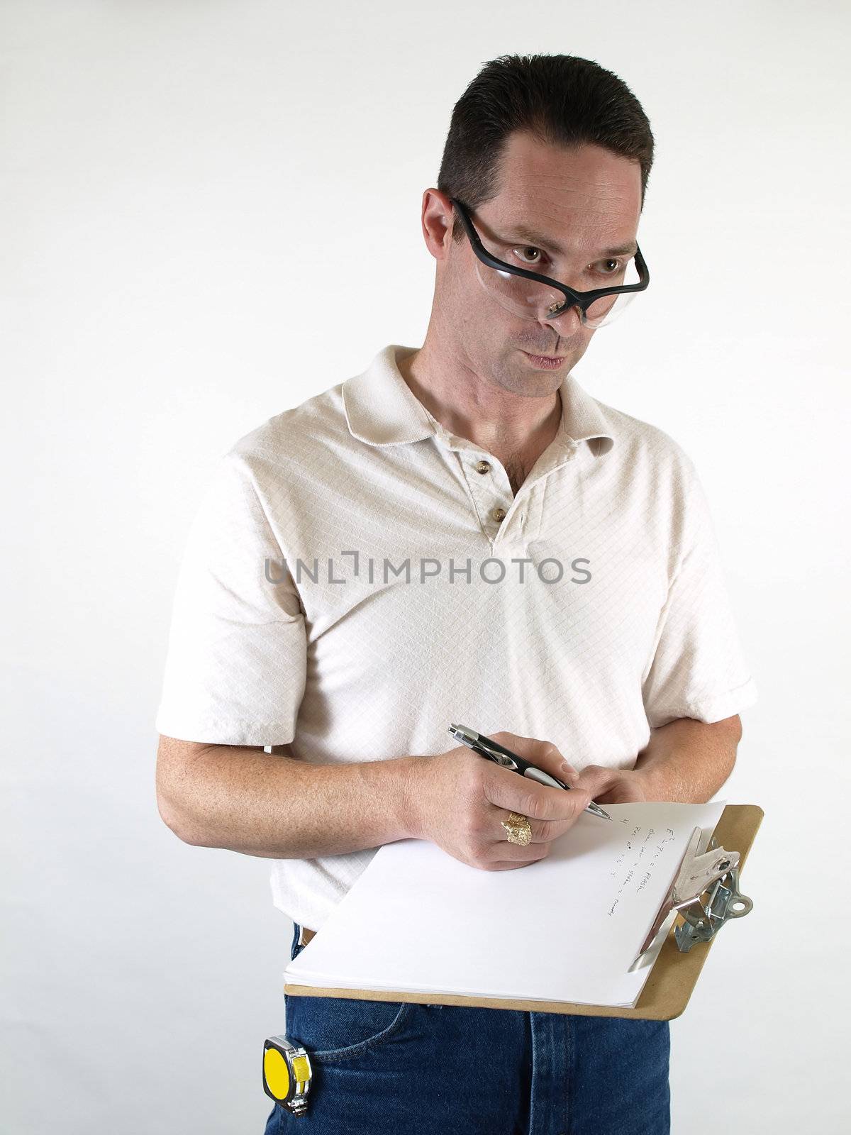 A male wearing safety glasses gives a look of doubt as he takes notes on his clipboard.
