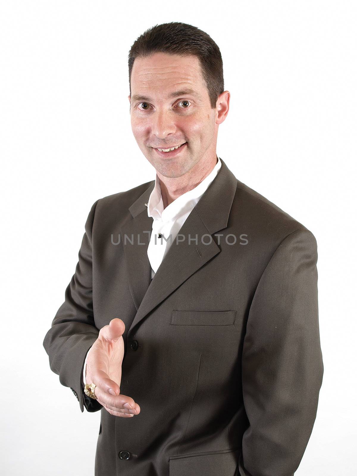 A smiling man in a business suit holds out his hand in a gesture of friendship.