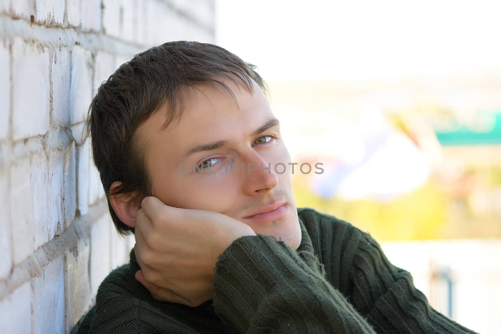 Portrait of the young man in a green sweater on an abstract background